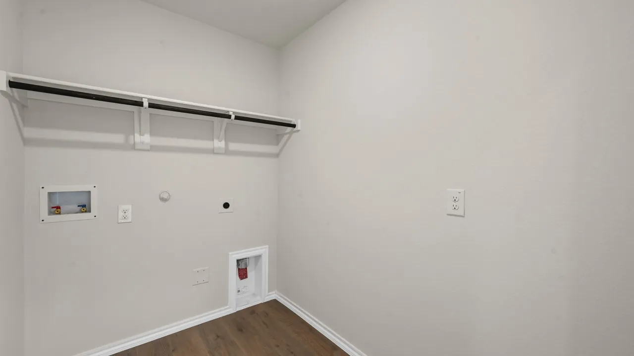 Laundry area featuring a wall-mounted shelf, hanging rod, and wood-finish flooring