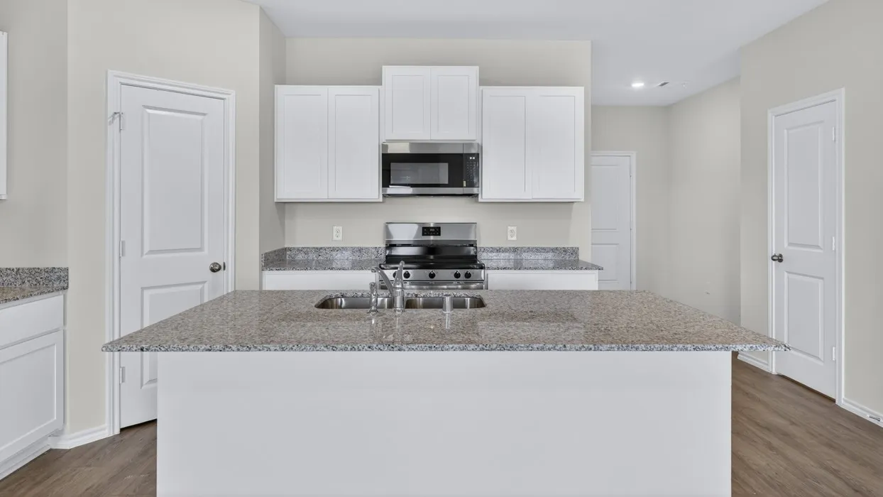 Kitchen island with an undermount sink and stainless steel faucet, complemented by white cabinetry, stainless steel appliances, and wood-finish flooring