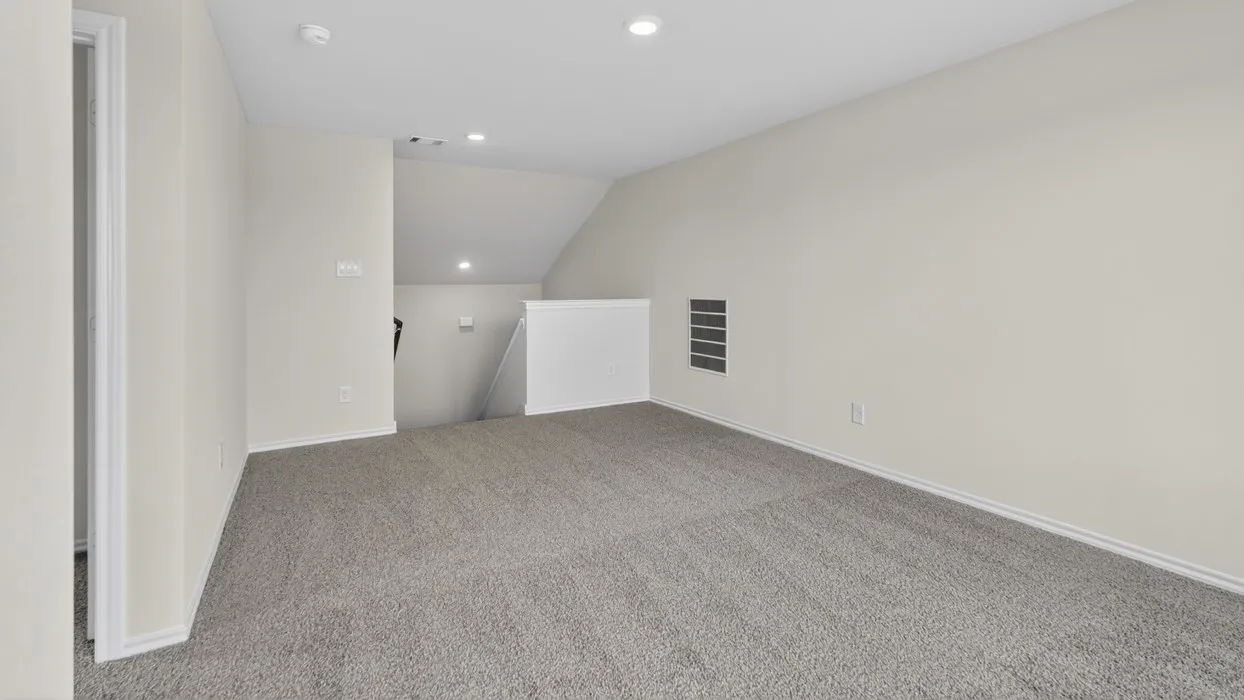 Carpeted open area with recessed lighting and a white half-wall railing