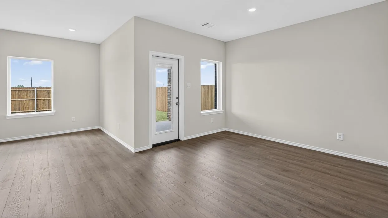 Wood-finish flooring with white trim, recessed lighting, and ample natural light from two windows and a glass-paneled door