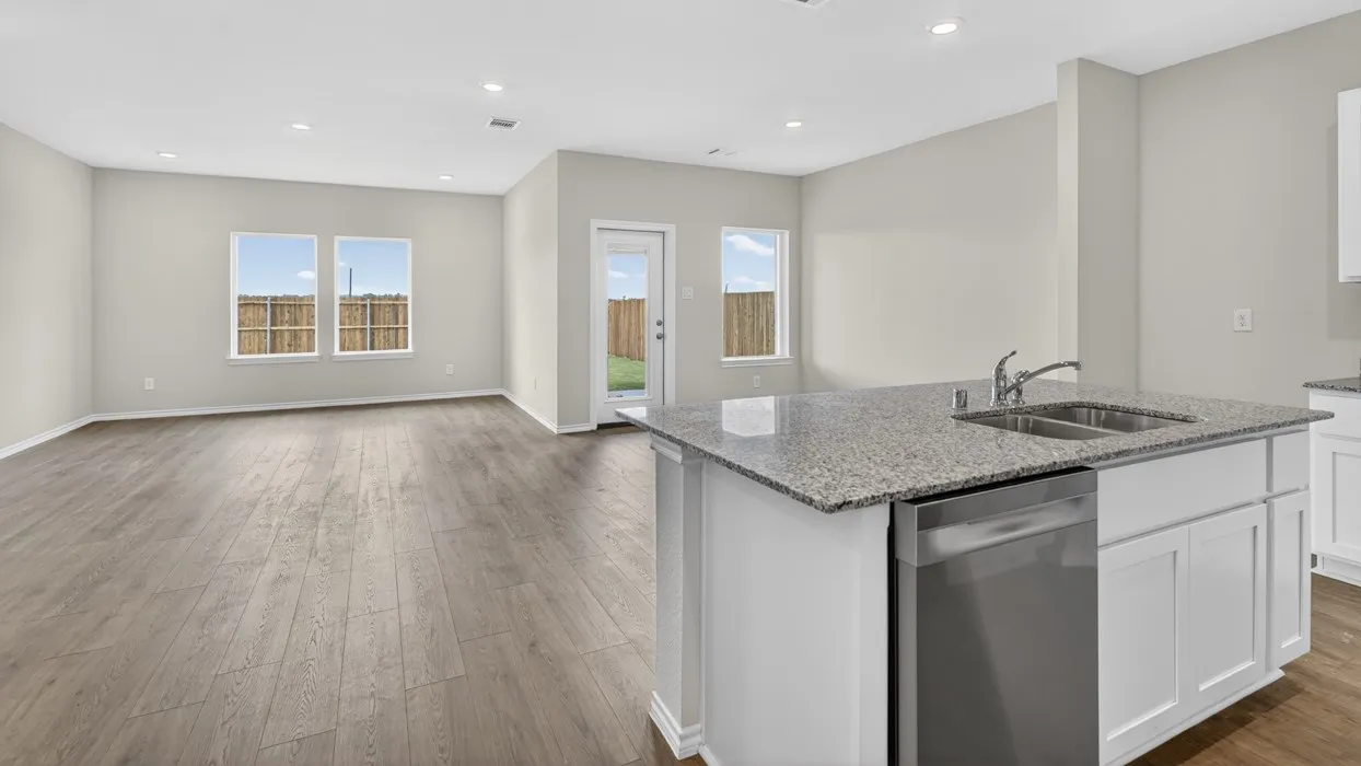 Open-concept living space featuring wood-finish flooring, recessed lighting, and a kitchen island with a double basin sink and stainless steel dishwasher