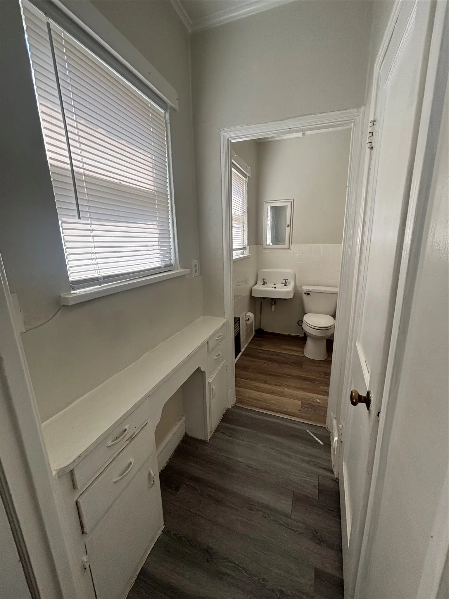 Built-in vanity with storage, wood-finish flooring, and white window blinds
