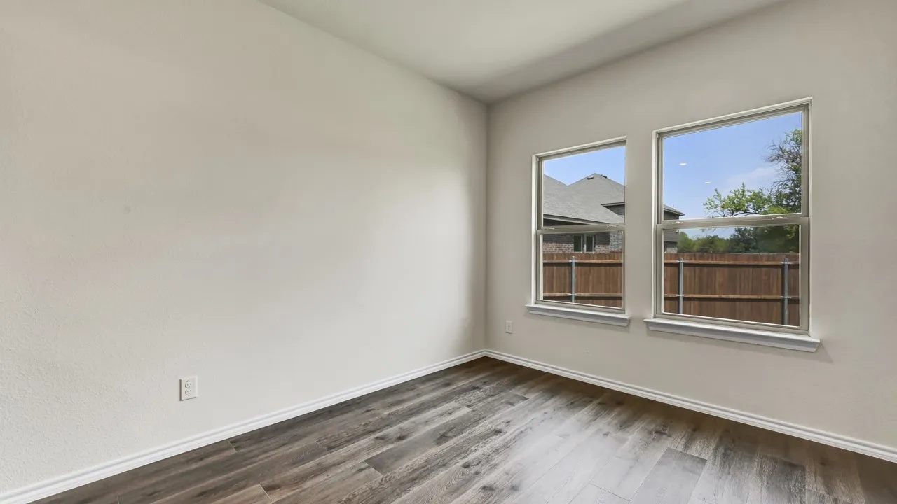 Light-filled room featuring two windows with white trim, wood-finish flooring, and light-toned walls