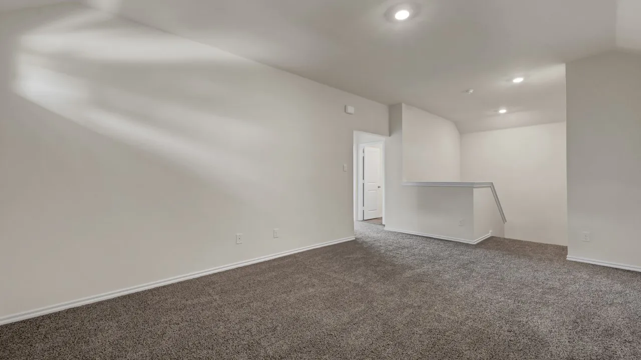 Carpeted flooring, recessed lighting, white wall finishes, and a partial stairwell with railing