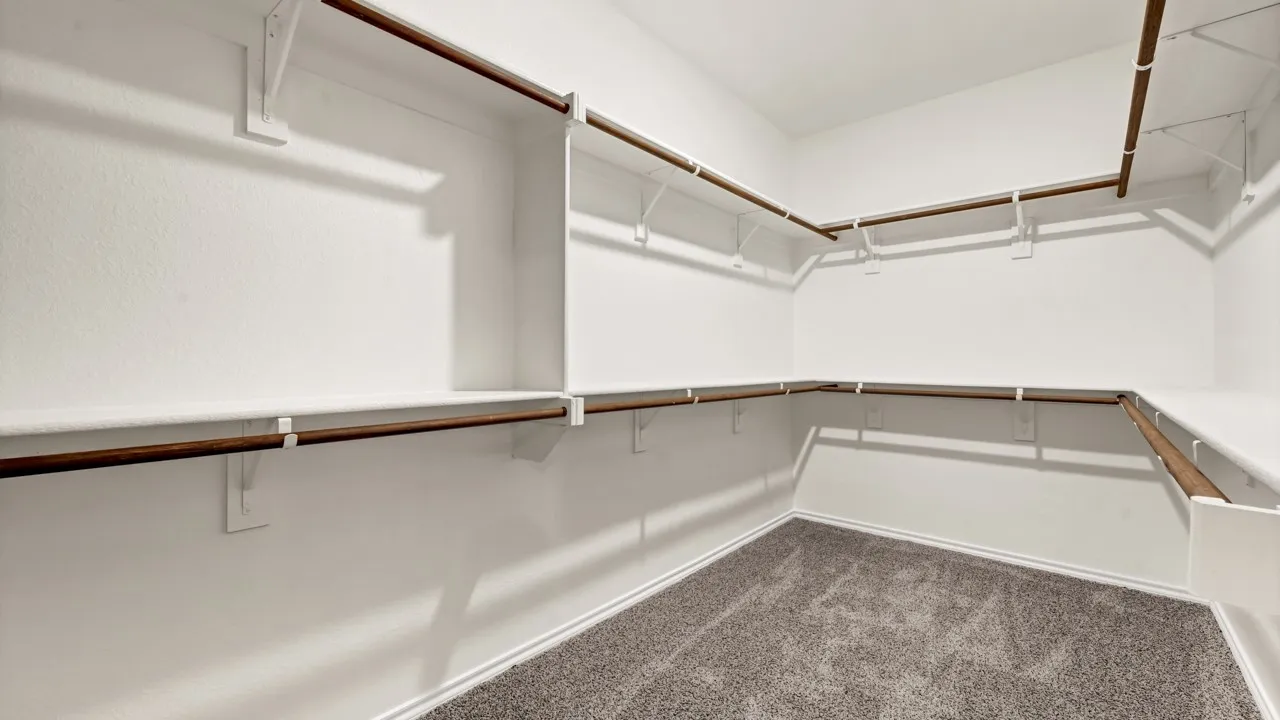 Wall-to-wall carpeting in a neutral tone, accompanied by white walls and shelving units with integrated hanging rods