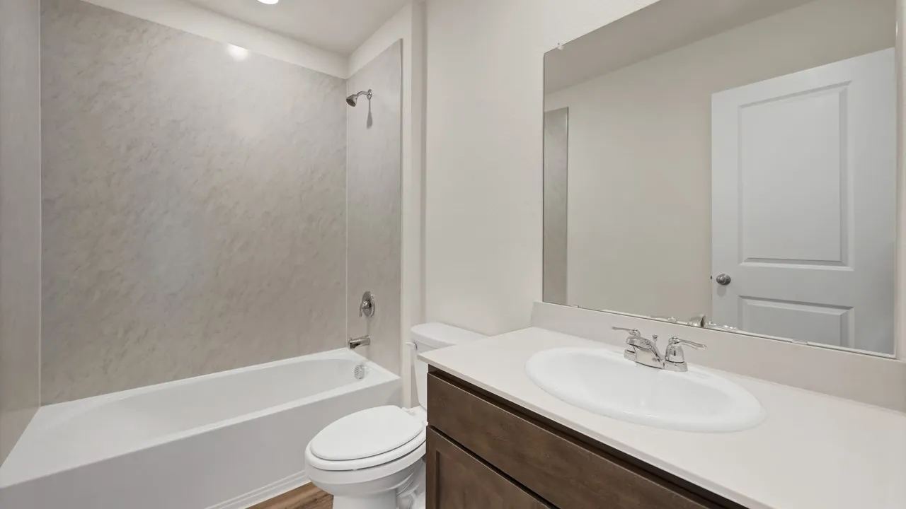 Built-in bathtub with a wall-mounted shower head, a single vanity with an integrated sink, and a large mirror