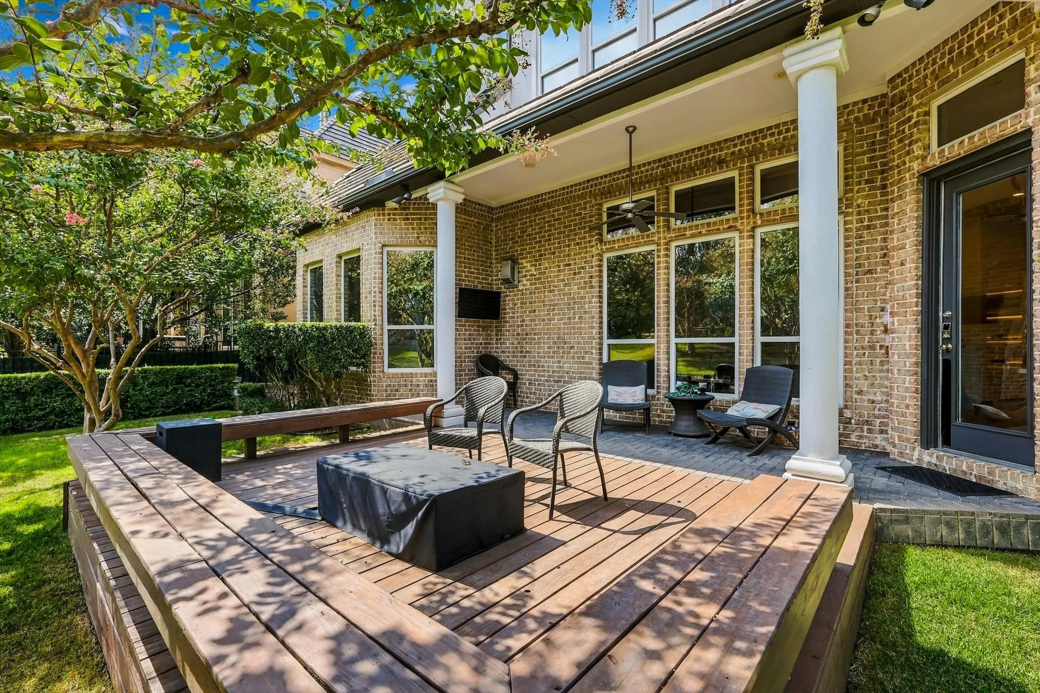 Stacked stone fireplace with a black insert, wood-finish flooring, bay windows, and crown molding