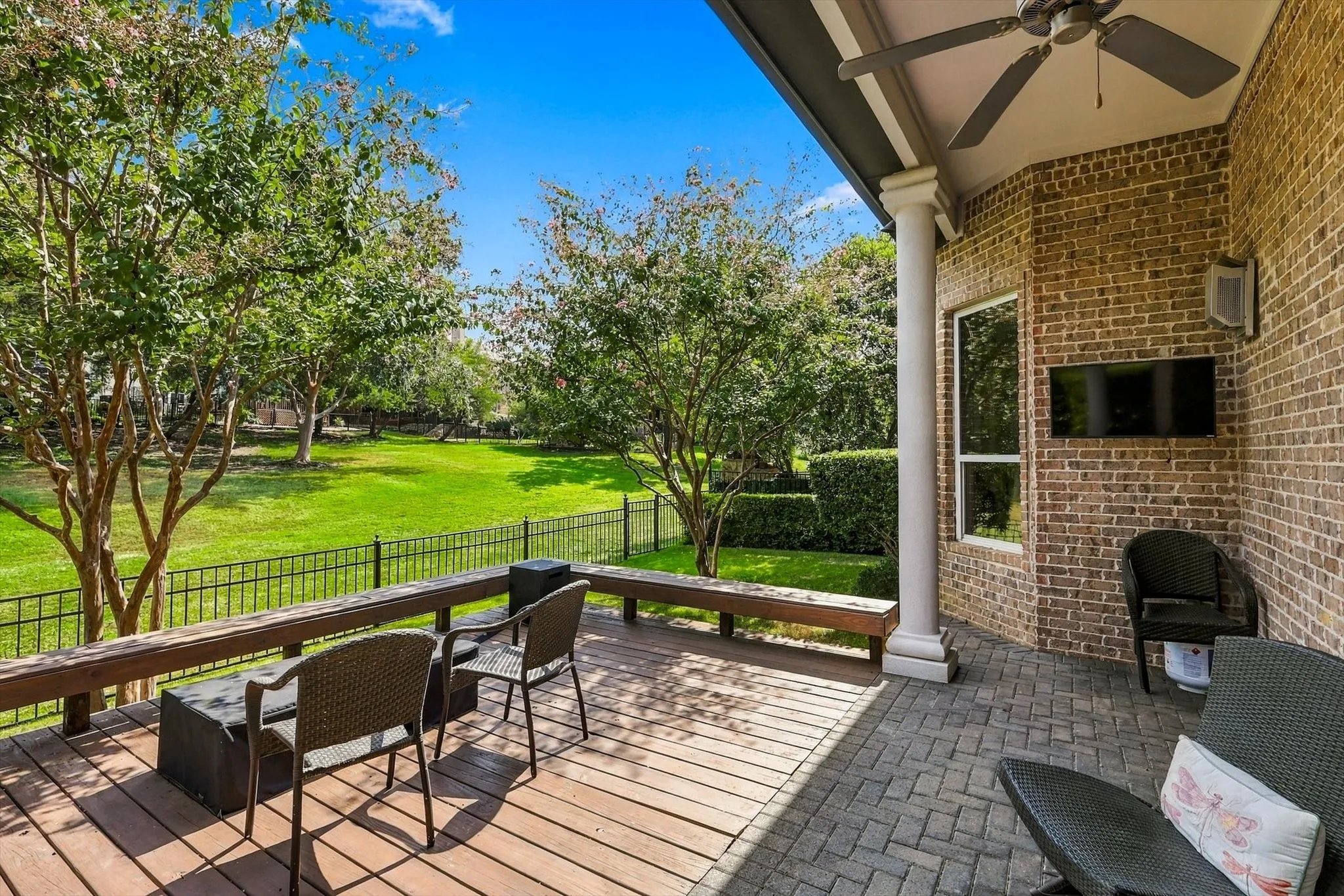 Covered patio featuring a ceiling fan, brick exterior, and a combination of wood-finish decking and paver flooring
