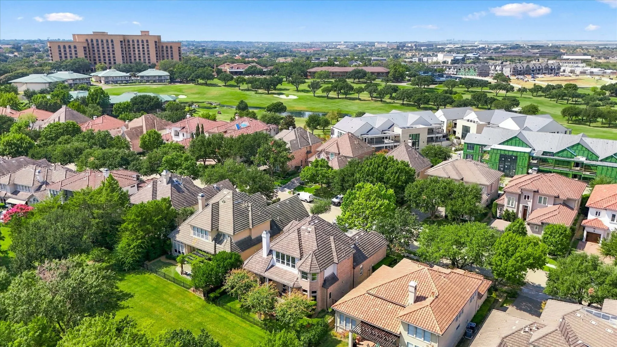 Aerial perspective showcasing a residential area with varied architectural styles, mature trees, and expansive green spaces