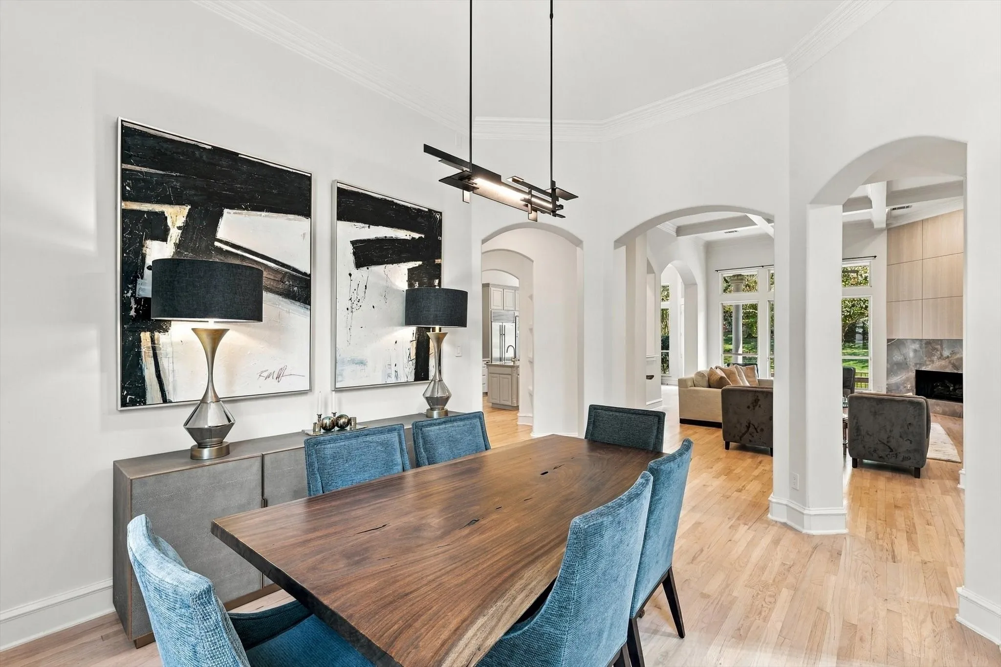 Hardwood flooring, arched doorways, a contemporary chandelier, crown molding, and high ceilings