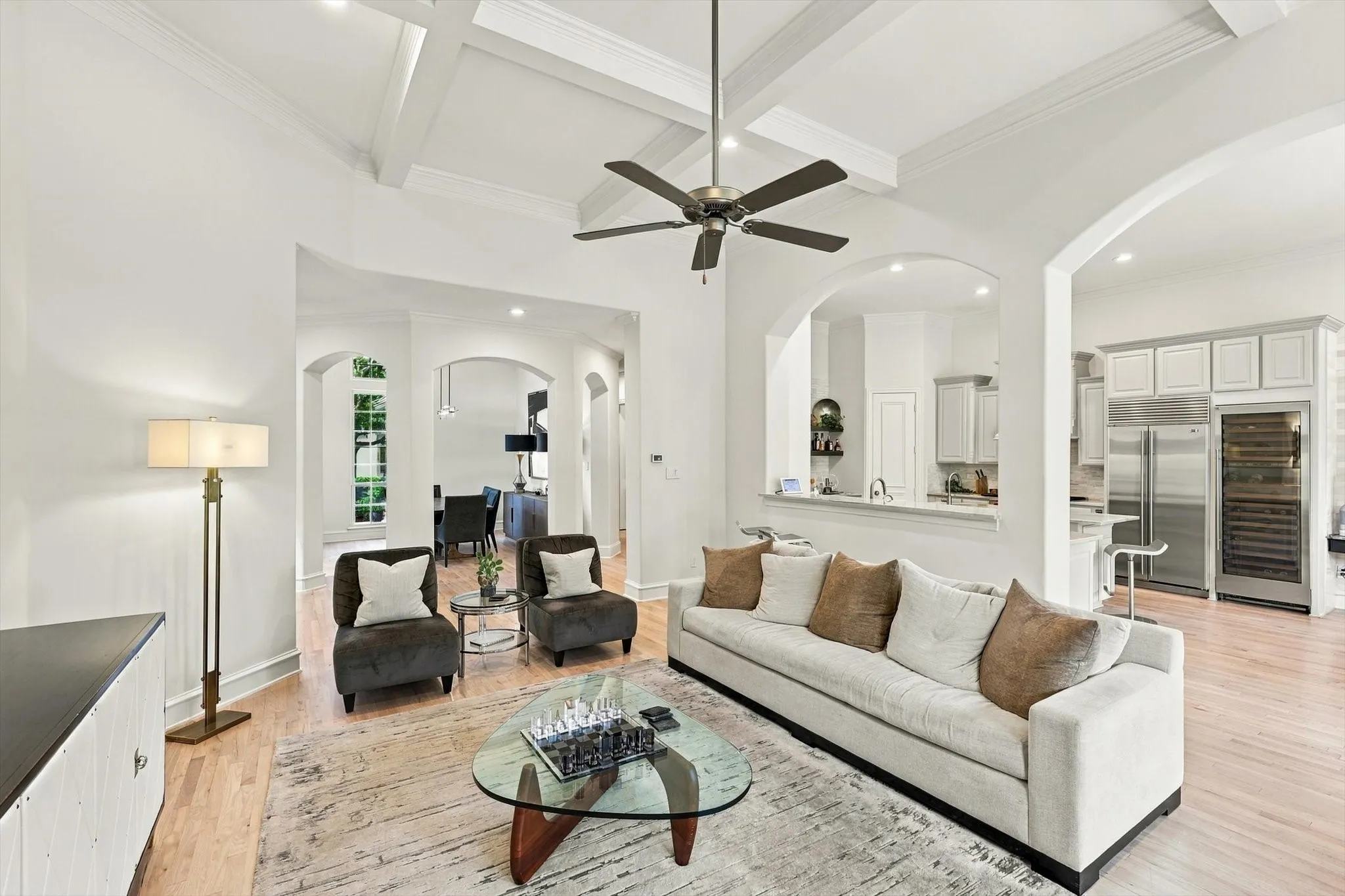 Coffered ceiling, hardwood flooring, arched doorways, recessed lighting, and built-in stainless steel appliances
