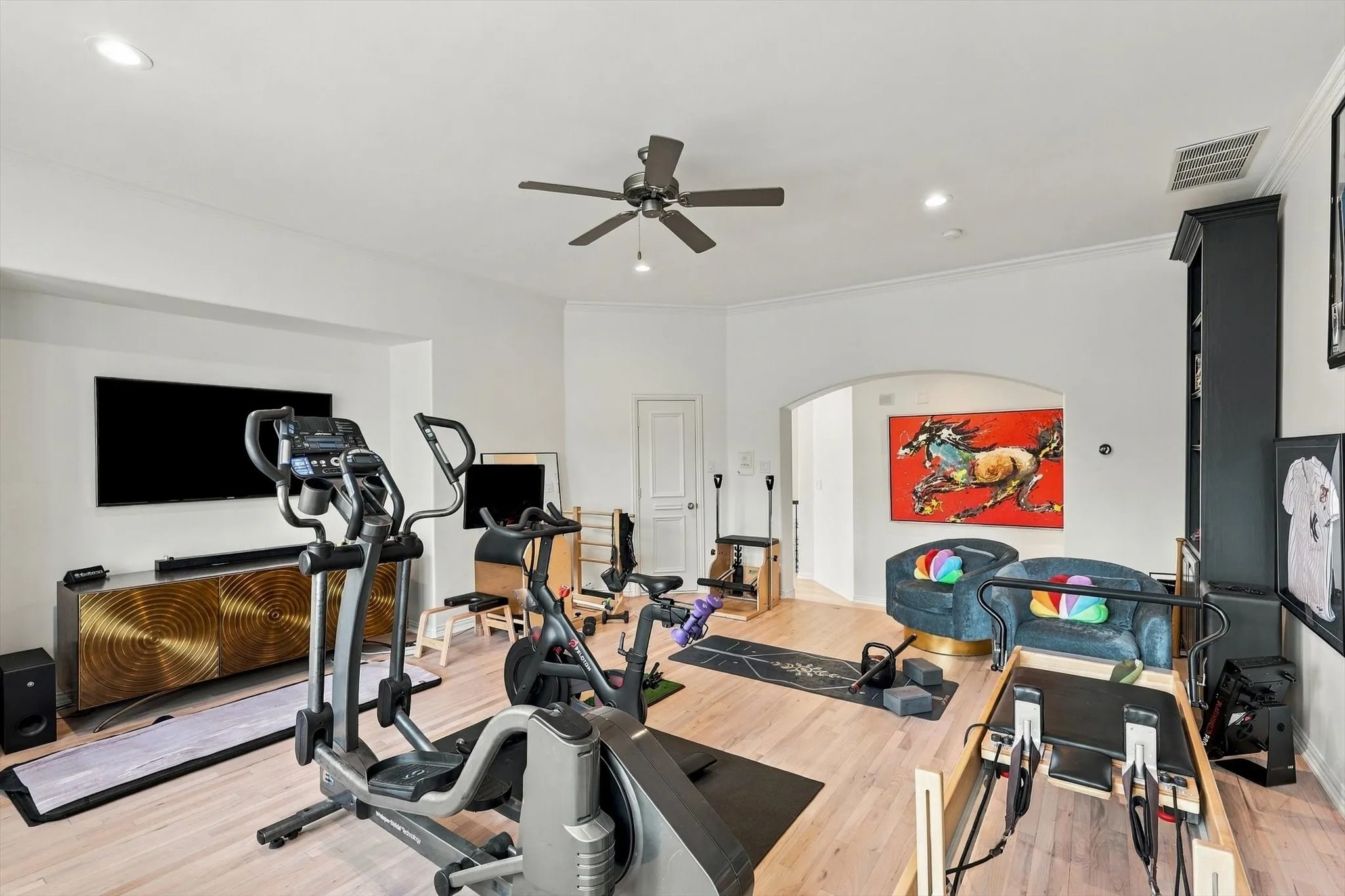 Recessed lighting, crown molding, a built-in media console, wood-finish flooring, and an arched doorway