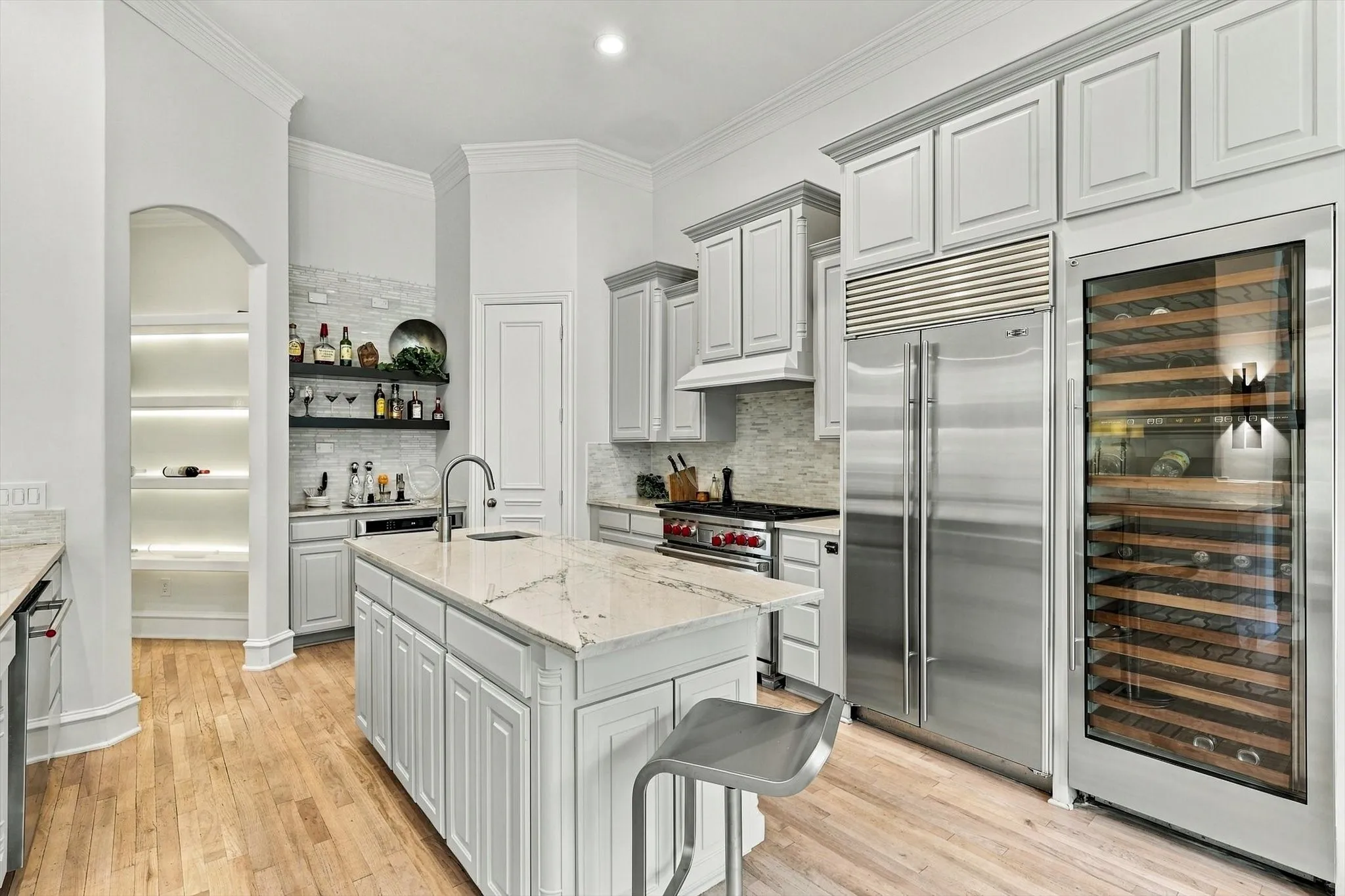 Gourmet kitchen featuring a center island with countertop, stainless steel appliances, a built-in wine cooler, and shaker-style cabinetry