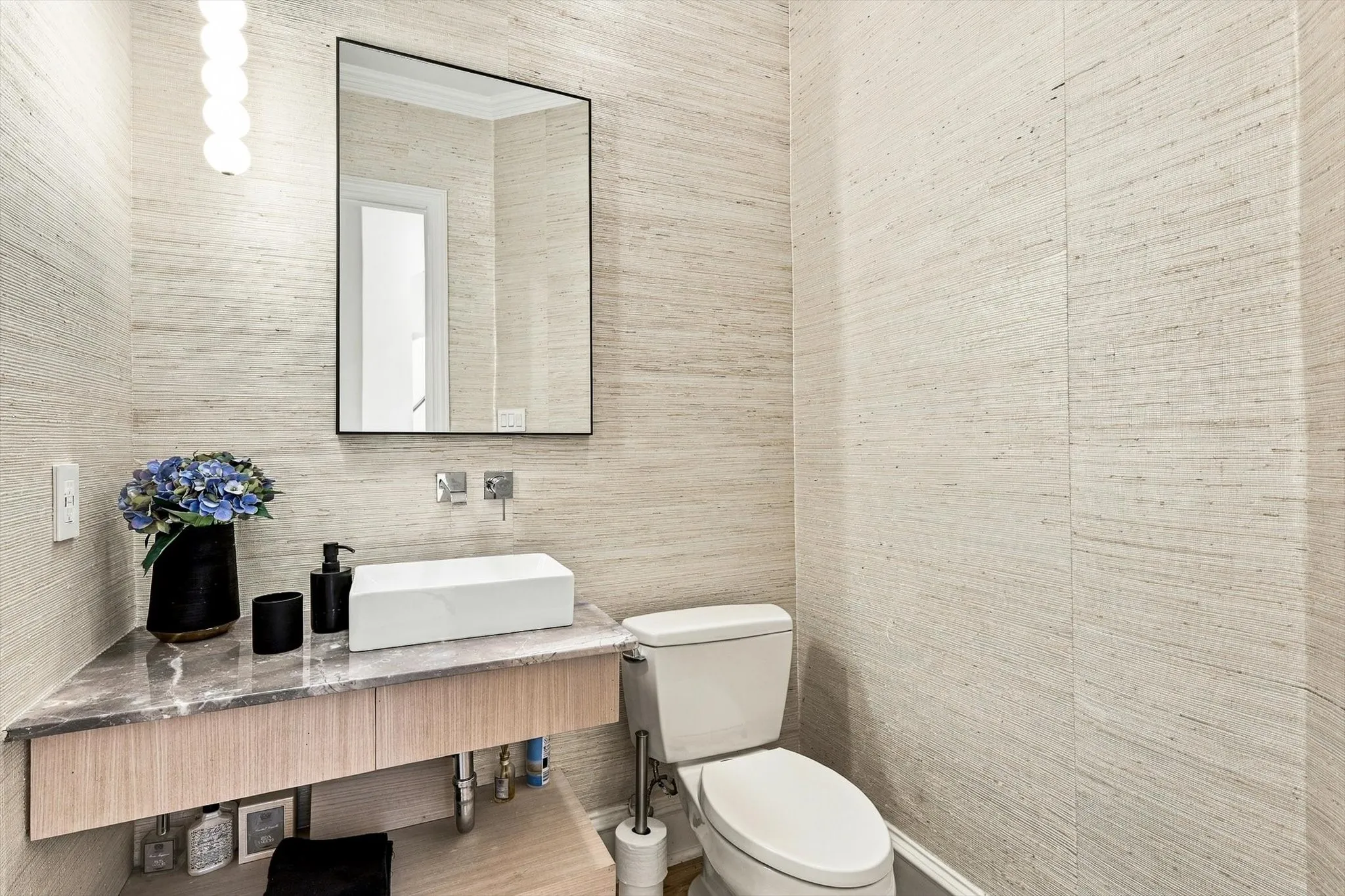 Powder room featuring a rectangular vessel sink, wall-mounted faucet, and a floating vanity with a stone countertop