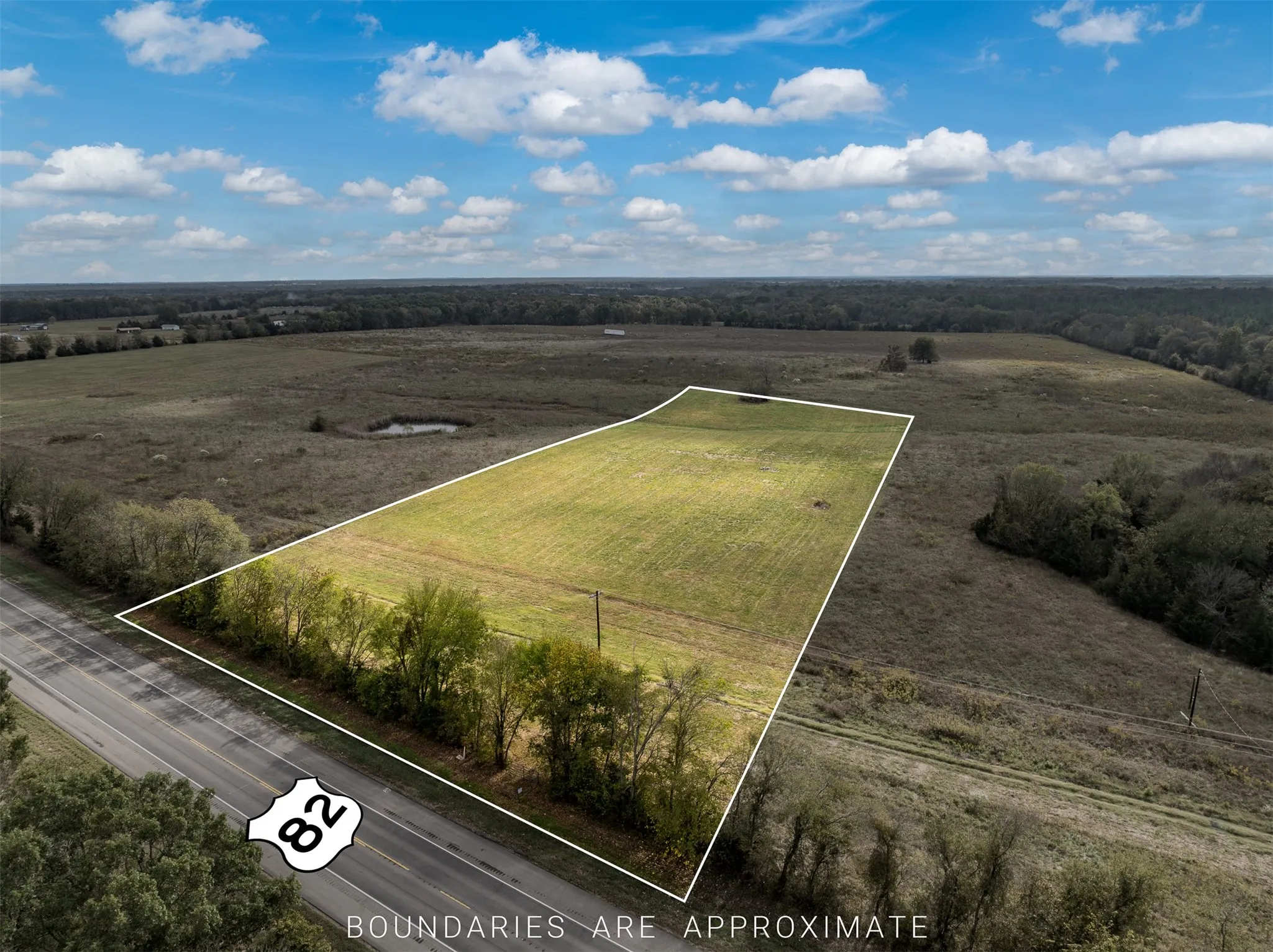 Expansive land parcel featuring clear boundaries, direct road frontage, and a partially wooded perimeter
