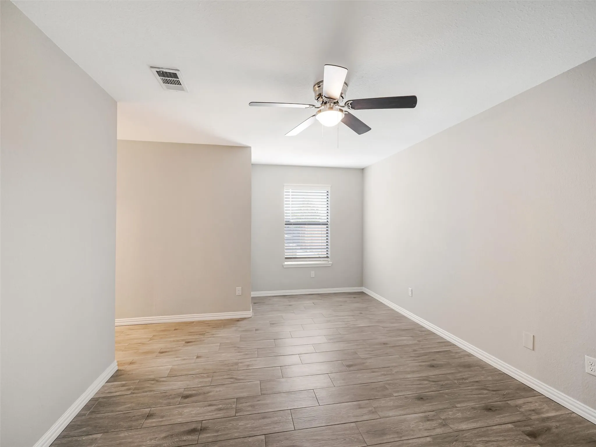 Wood-look tile flooring, ceiling fan with integrated lighting, and window with blinds