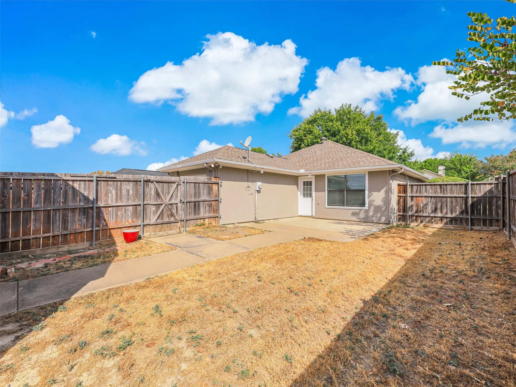 Private fenced yard with concrete patio, wood fencing, and a side access gate