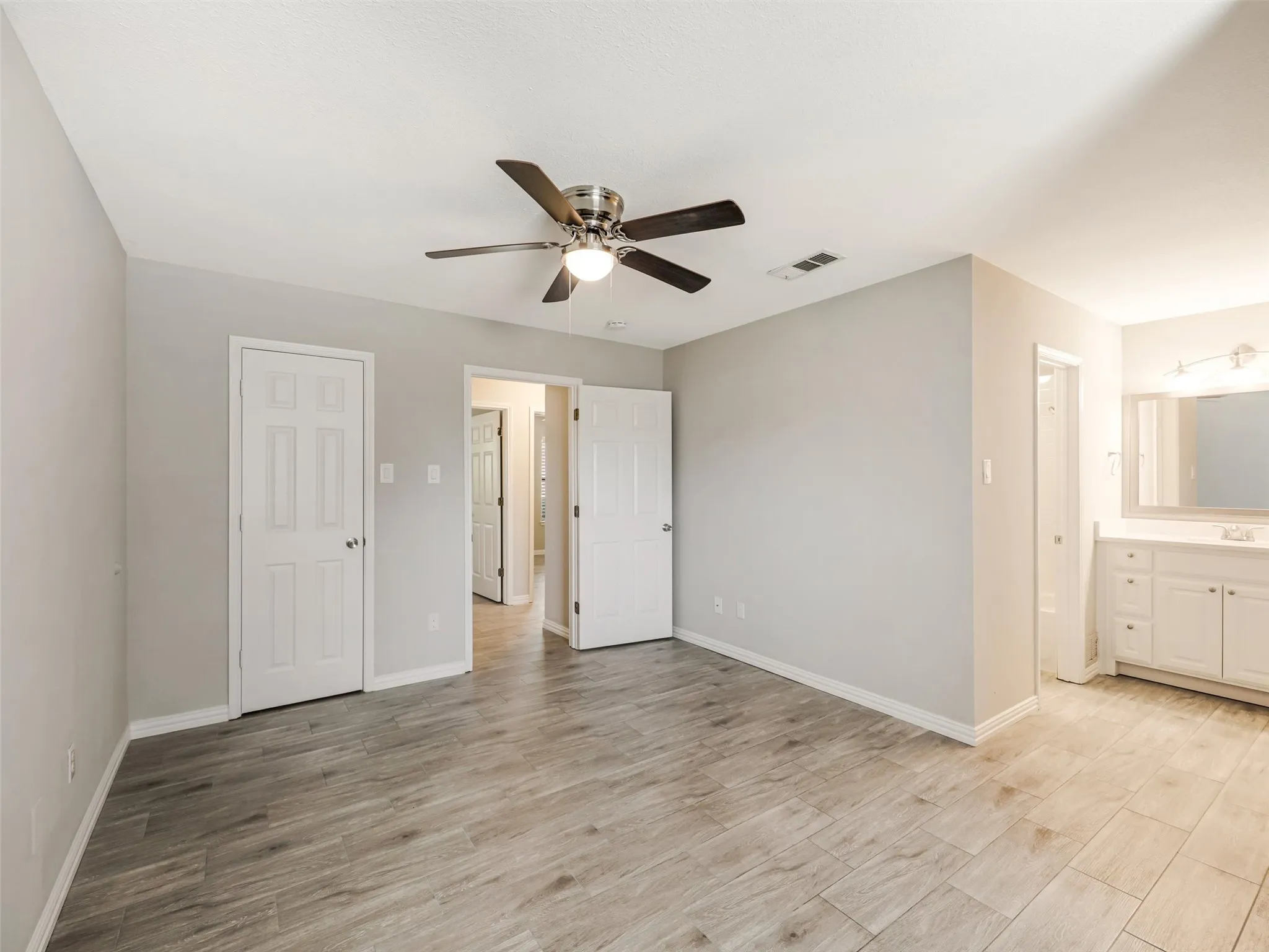 Spacious room with wood-finish flooring and a ceiling fan