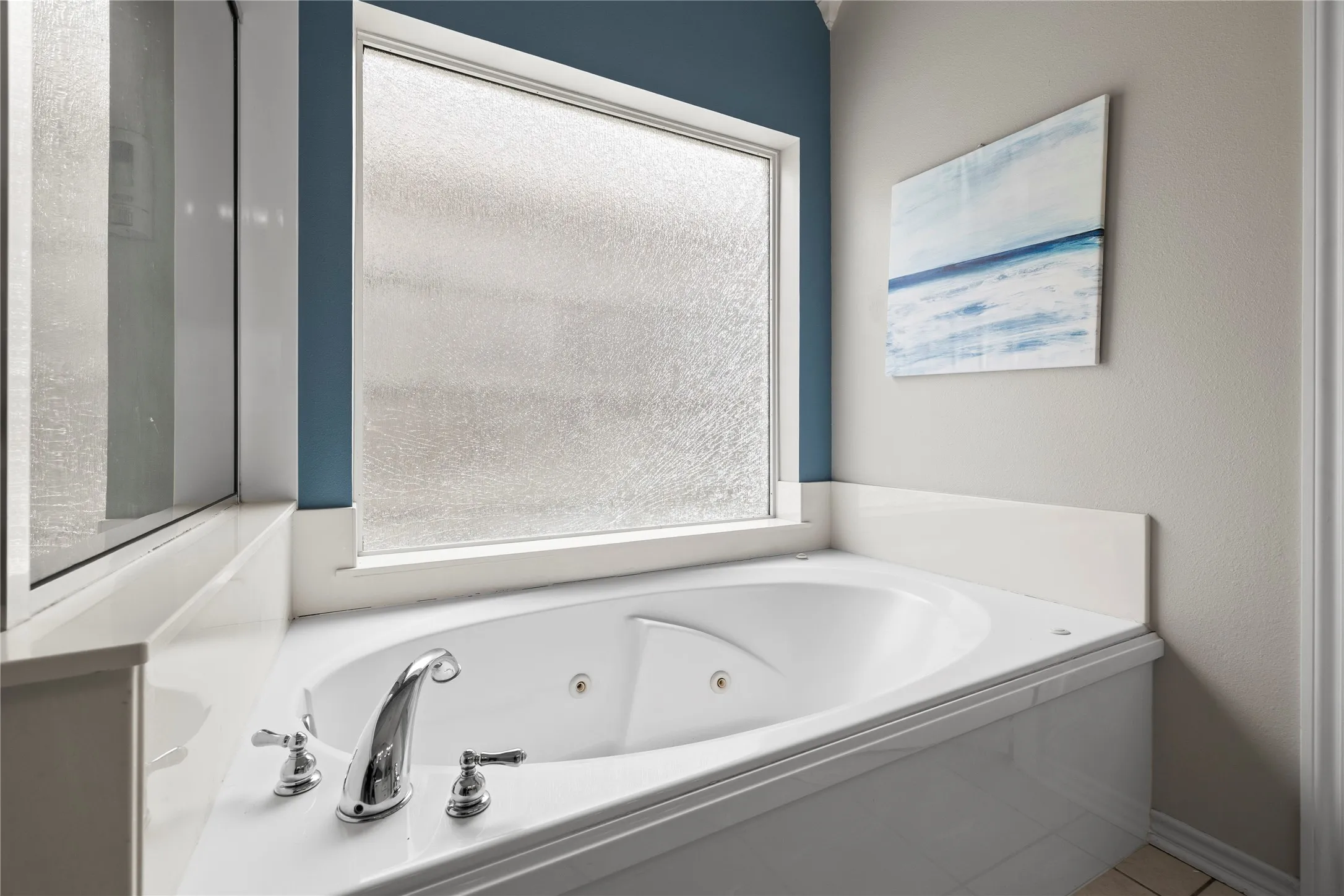 Corner jetted tub with polished chrome fixtures and a frosted window