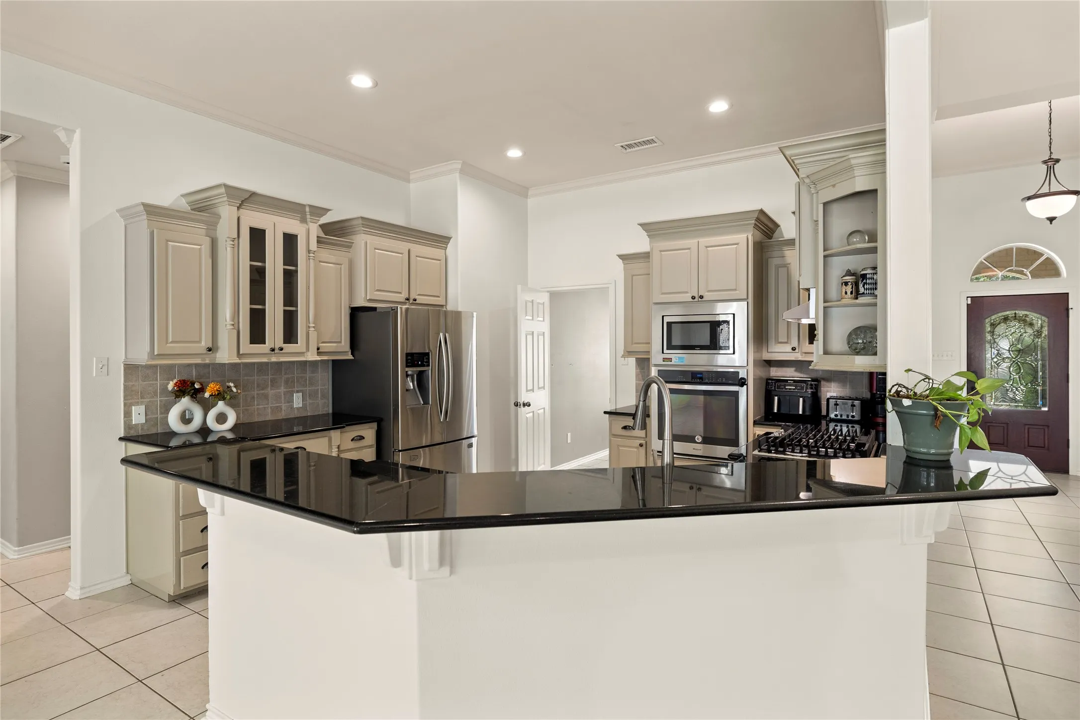 Kitchen featuring dark countertops, light-toned cabinetry, stainless steel appliances, and a tiled backsplash
