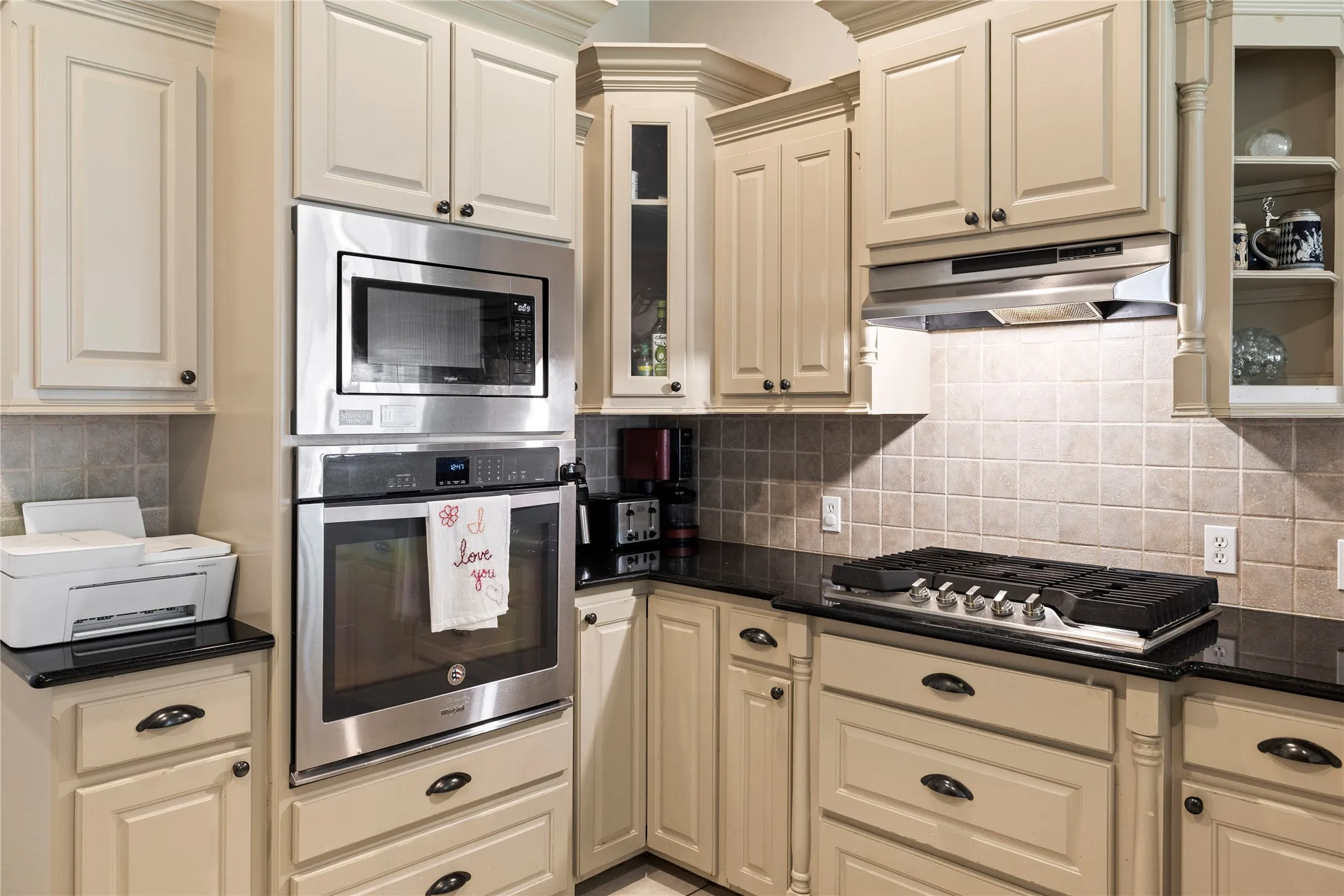 Stainless steel wall oven, microwave, and range hood complement the gas cooktop
