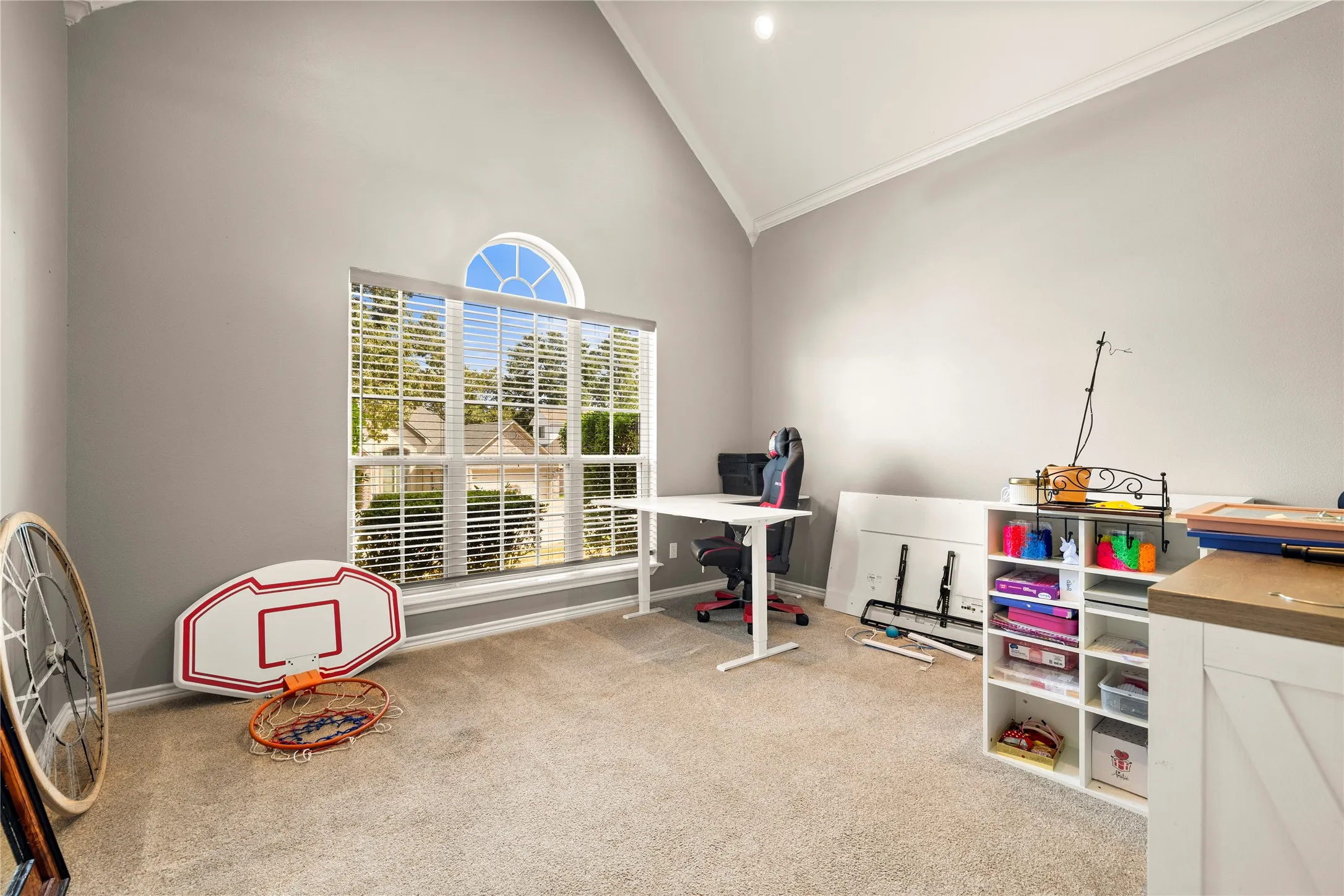 Vaulted ceiling with crown molding, window with arch top, and neutral carpeting