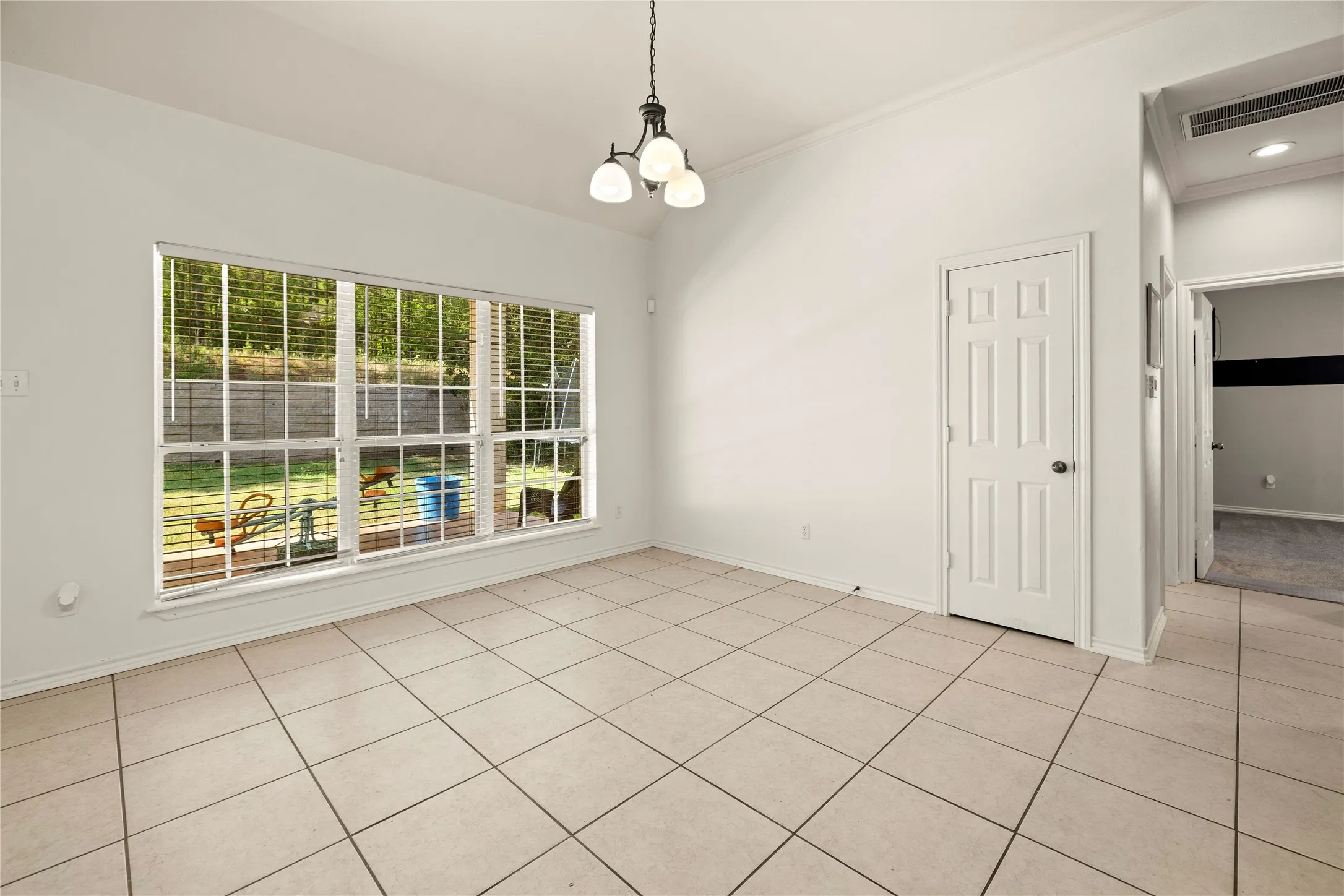 Vaulted ceilings, tile flooring, window blinds, and a multi-pane window