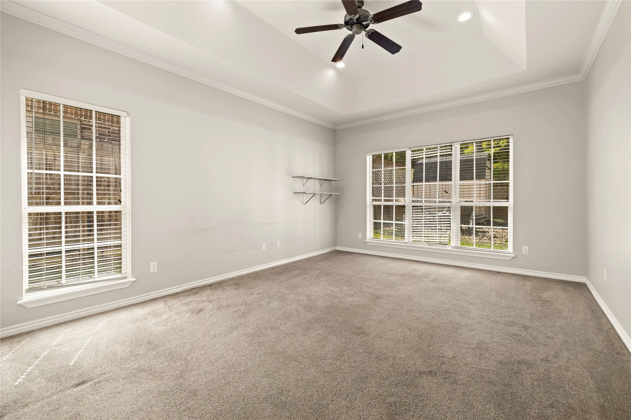 Recessed lighting, ceiling fan, tray ceiling, crown molding, and large windows