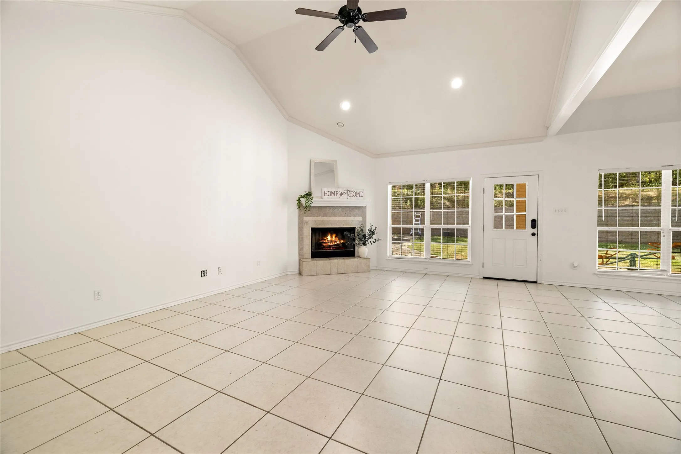 Vaulted ceiling with a ceiling fan and recessed lighting, corner fireplace, ceramic tile flooring, and multiple windows