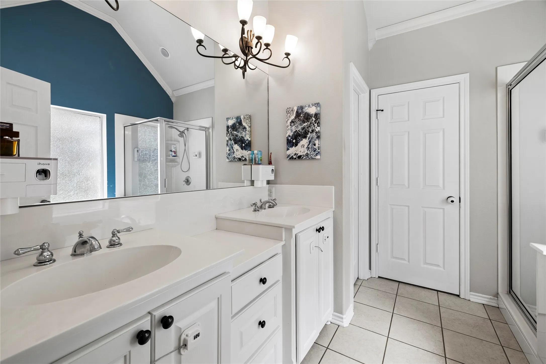 Double vanity with integral sinks, white cabinetry, chrome fixtures, and a large mirror