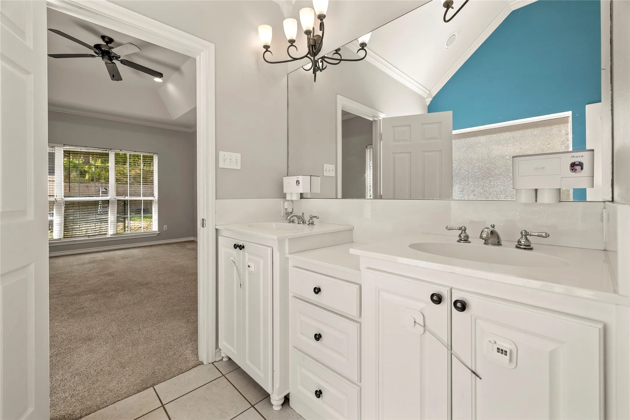 Dual white vanities with integrated sinks, chrome fixtures, tile flooring, and a large wall-mounted mirror