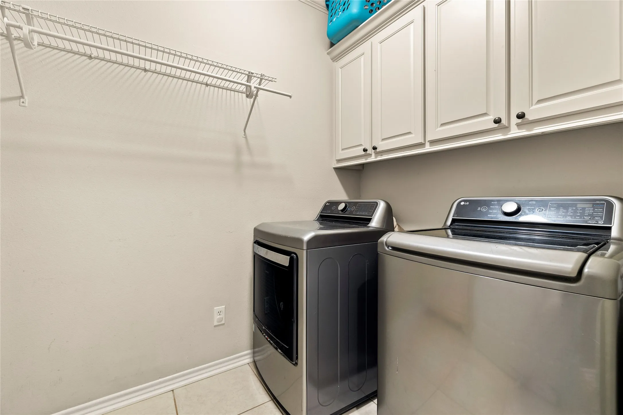 Upper cabinetry with black hardware, wire shelving, and tiled flooring