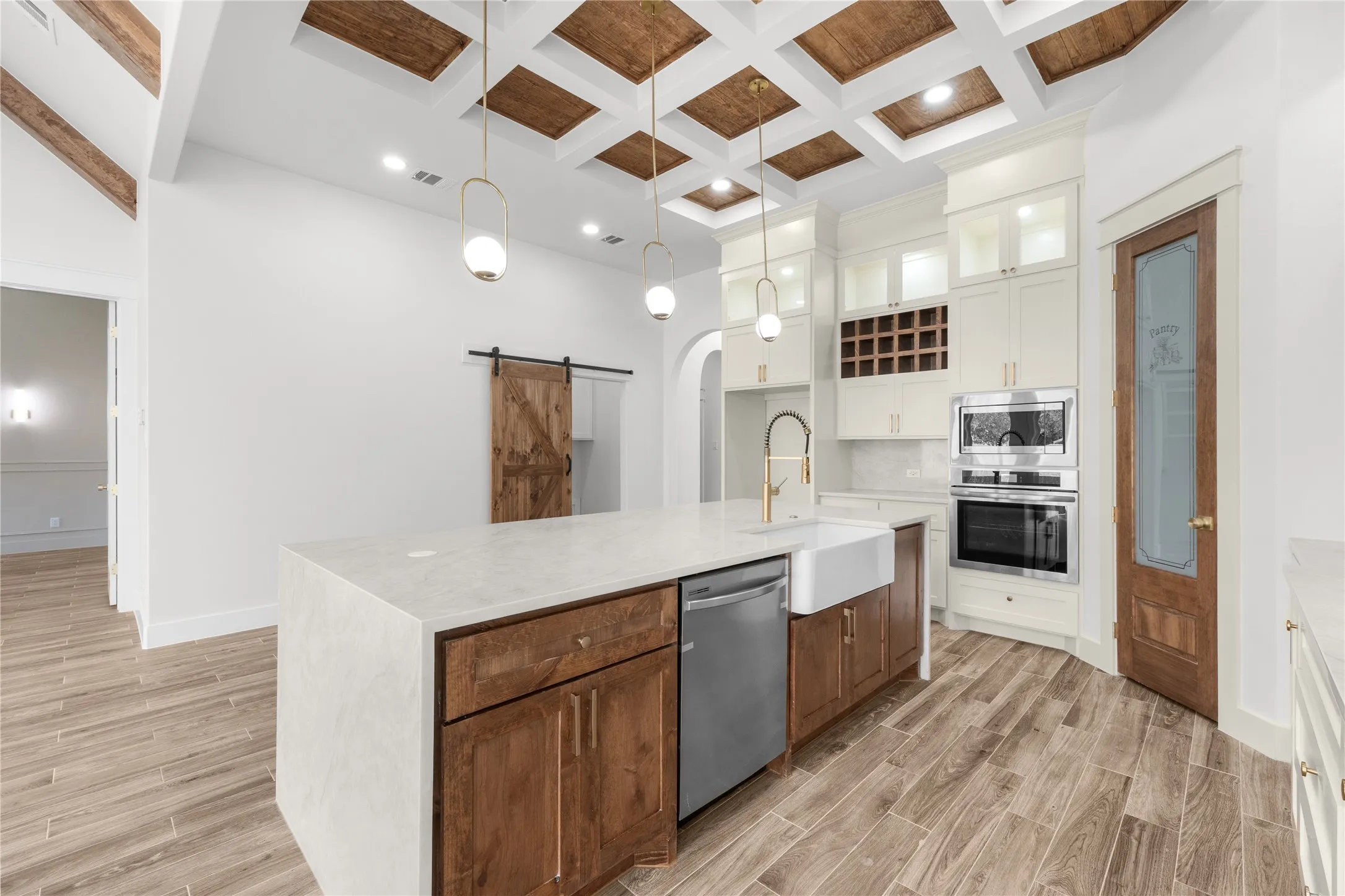 Kitchen featuring wood-finish flooring, a large island with a white countertop, farmhouse sink, and integrated dishwasher