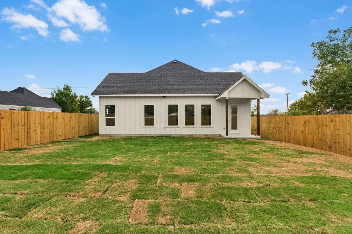 Expansive backyard featuring a new privacy fence, fresh sod, and a covered back patio with wood-tone posts