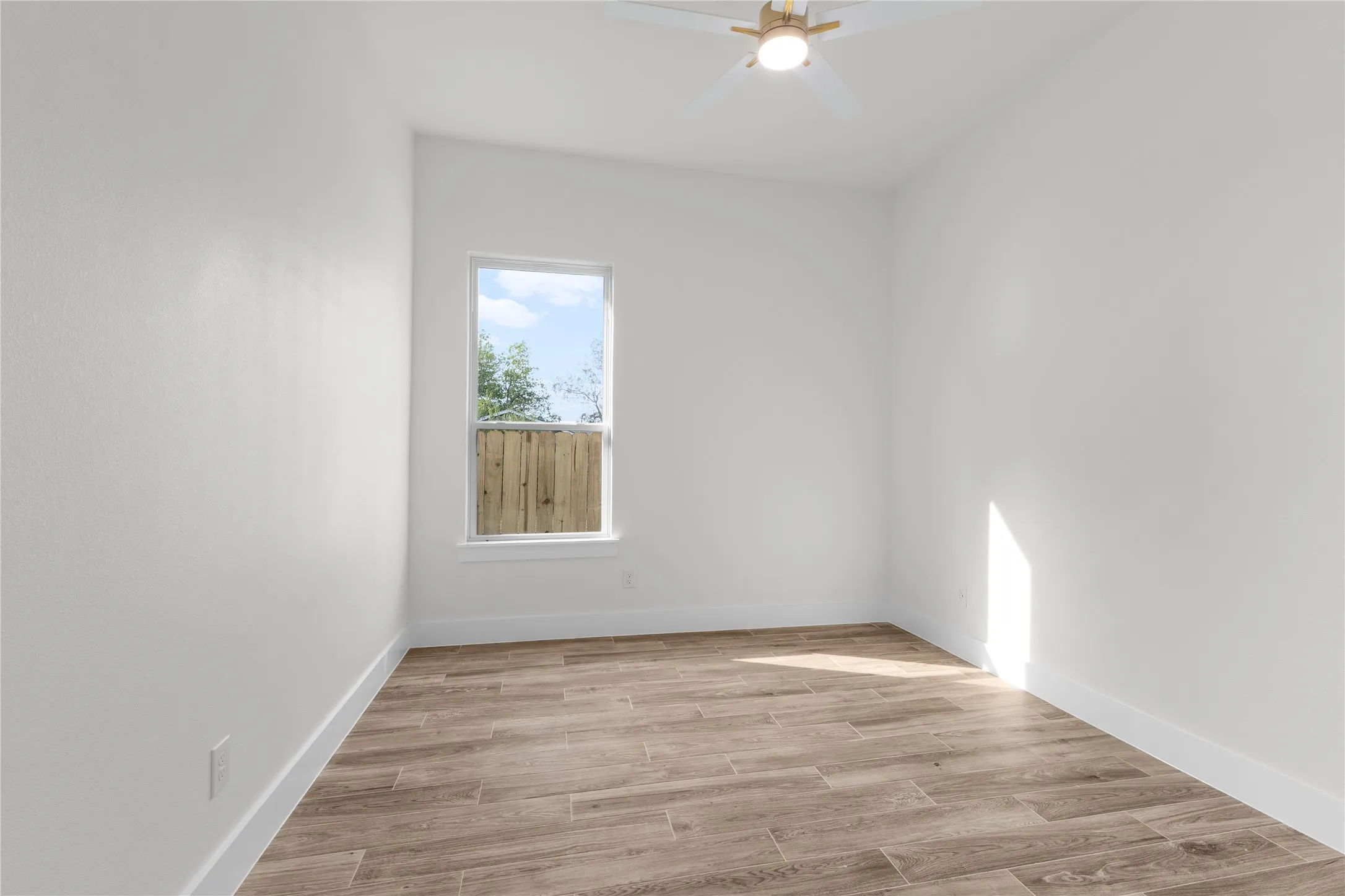 Wood-finish tile flooring, recessed window, ceiling fan, and white walls