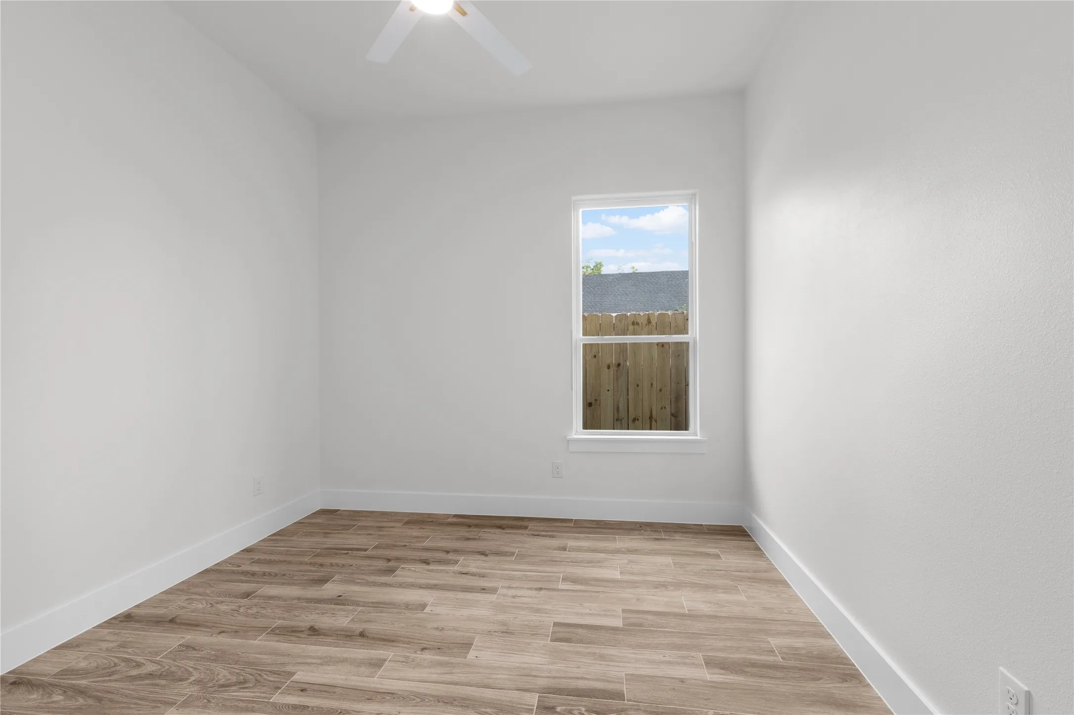 Wood-finish flooring, white walls, and a ceiling fan