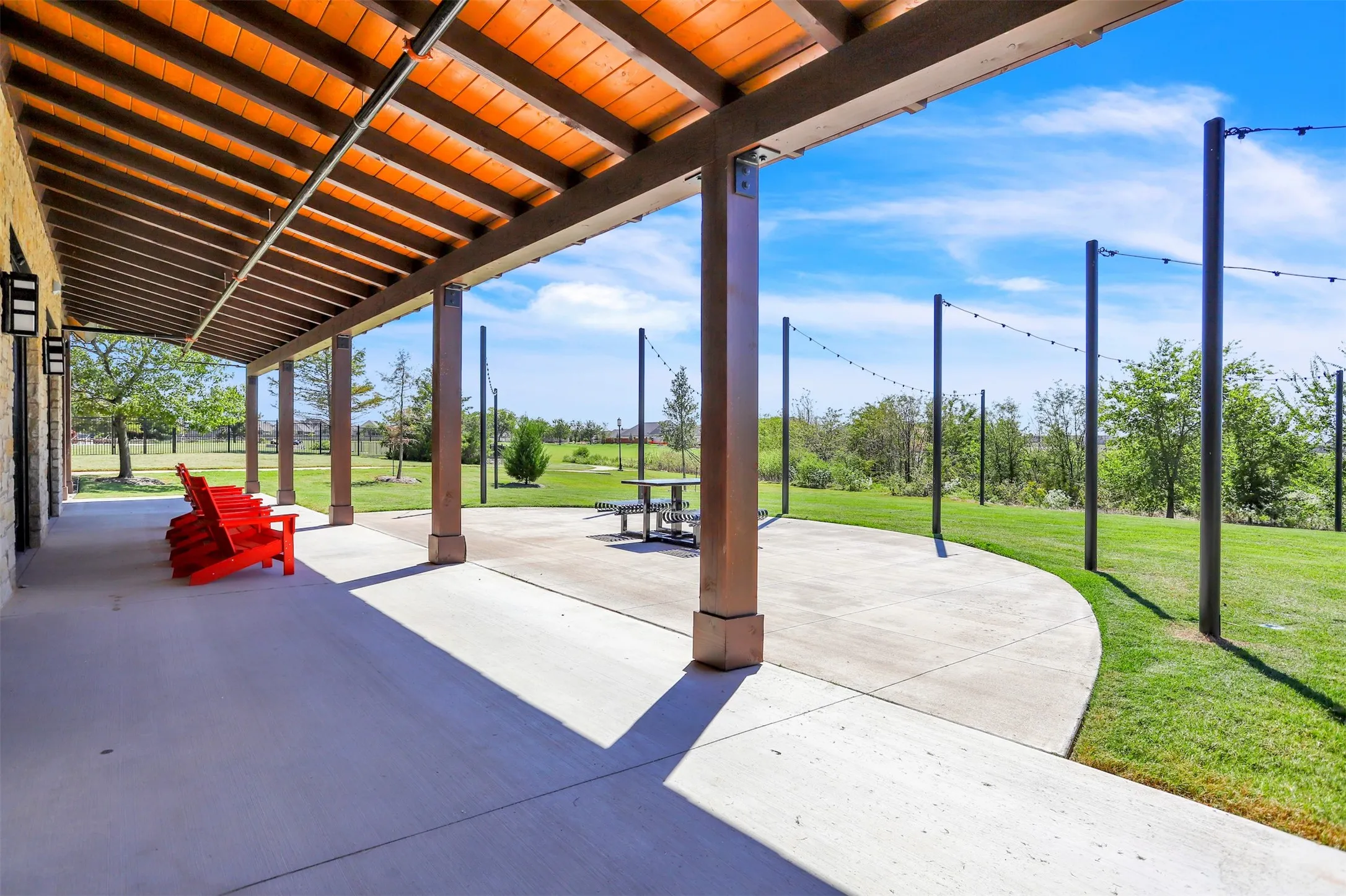 Expansive covered patio featuring a wood-finish ceiling, robust support columns, and built-in exterior lighting