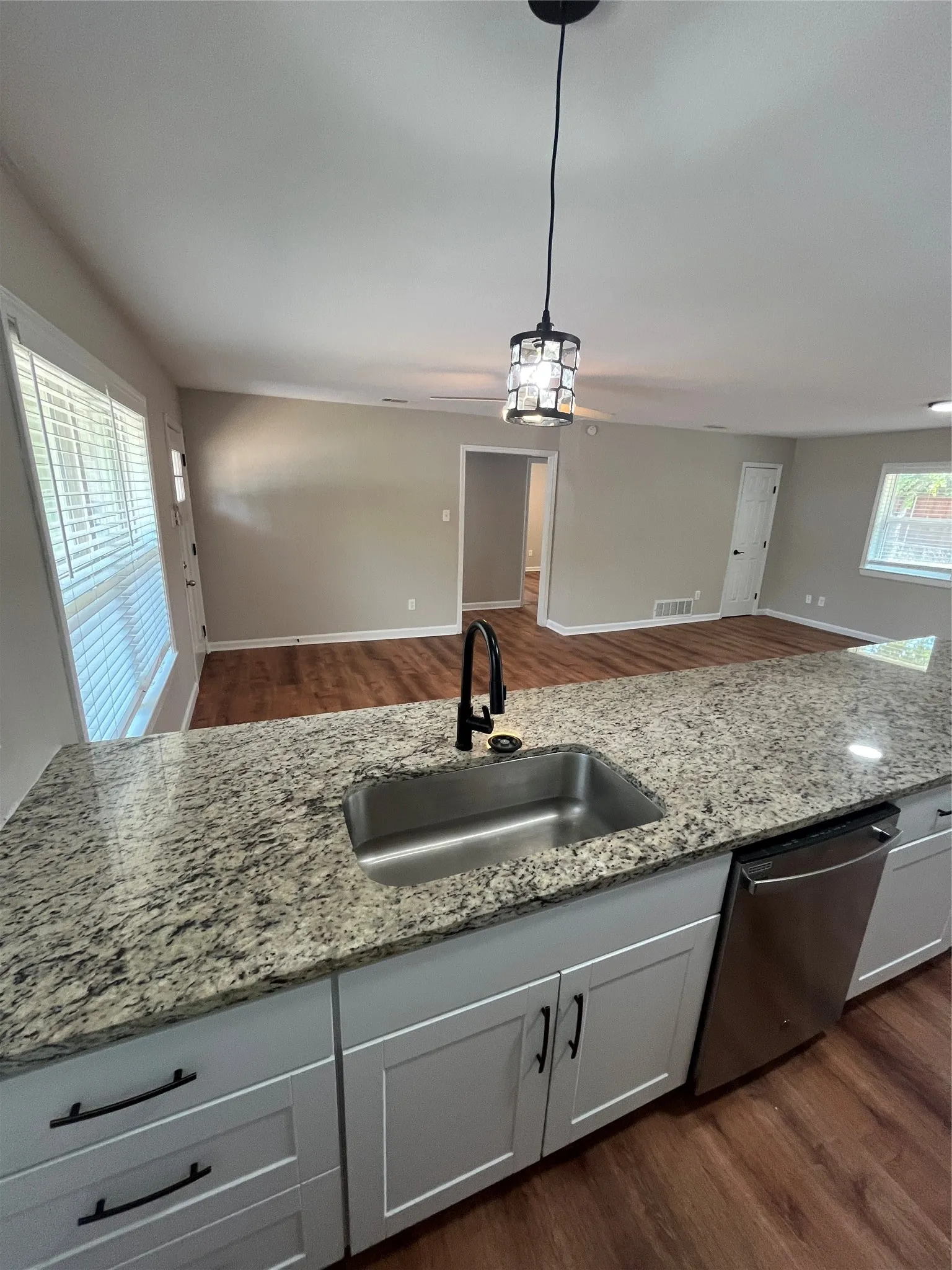 Kitchen island with a stainless steel sink, black faucet, and light-toned countertop