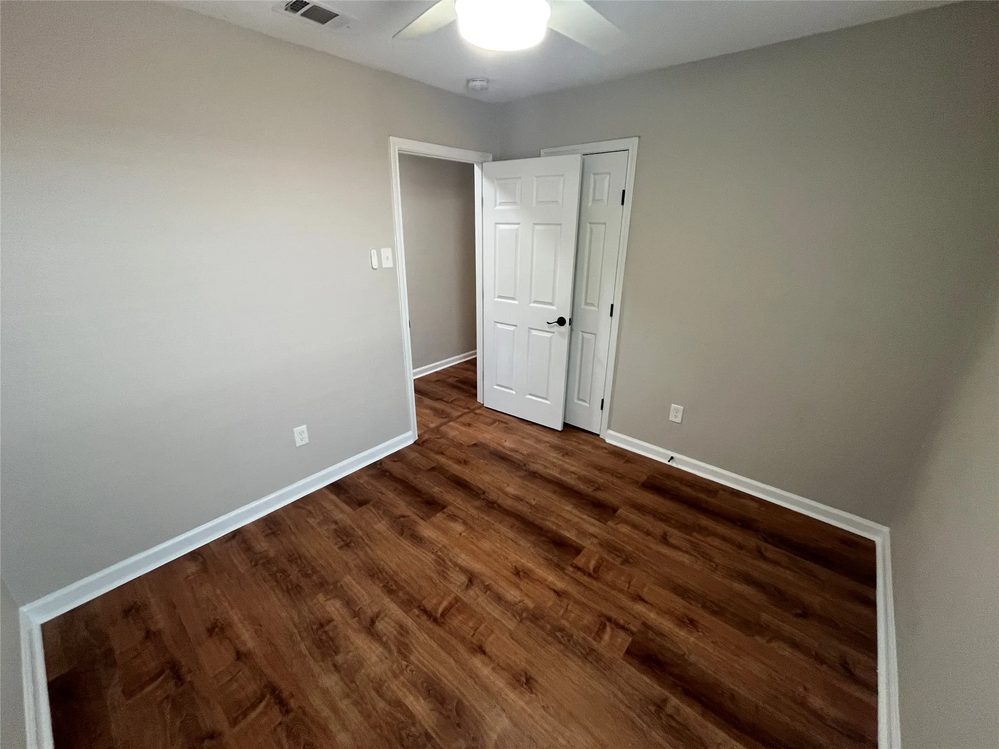 Wood-finish flooring, light gray walls, white trim, and a ceiling fan with integrated lighting