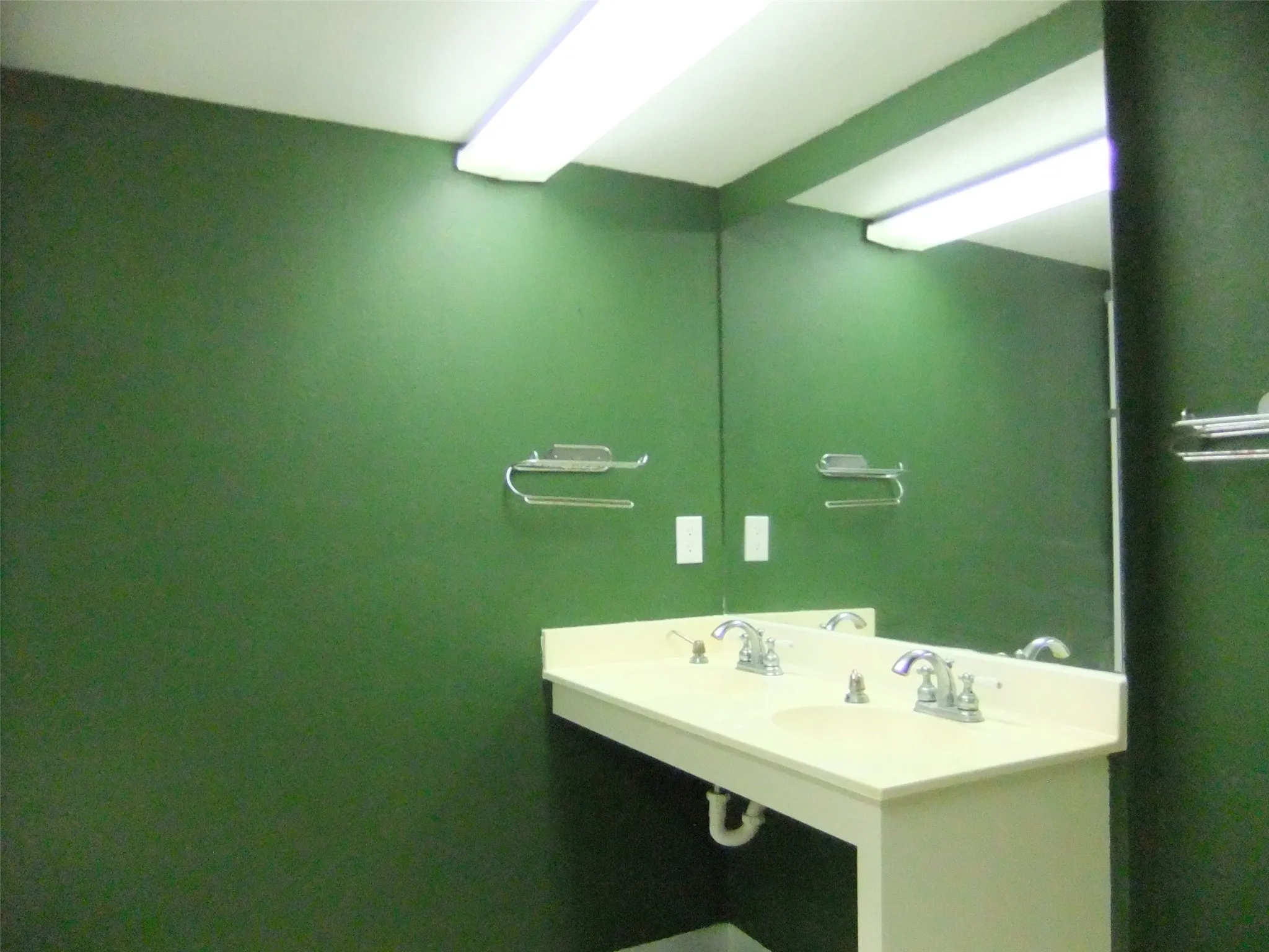 Mens restroom in foyer Double vanity with integrated sinks, chrome fixtures, and a large wall-mounted mirror