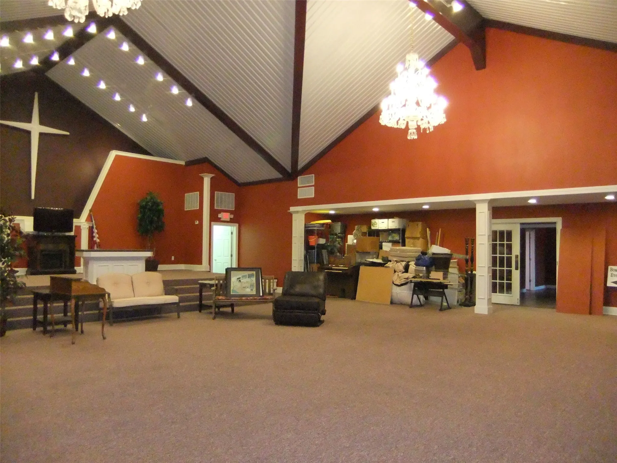 Vaulted ceiling with exposed beams, recessed lighting, chandelier, raised platform, and french doors