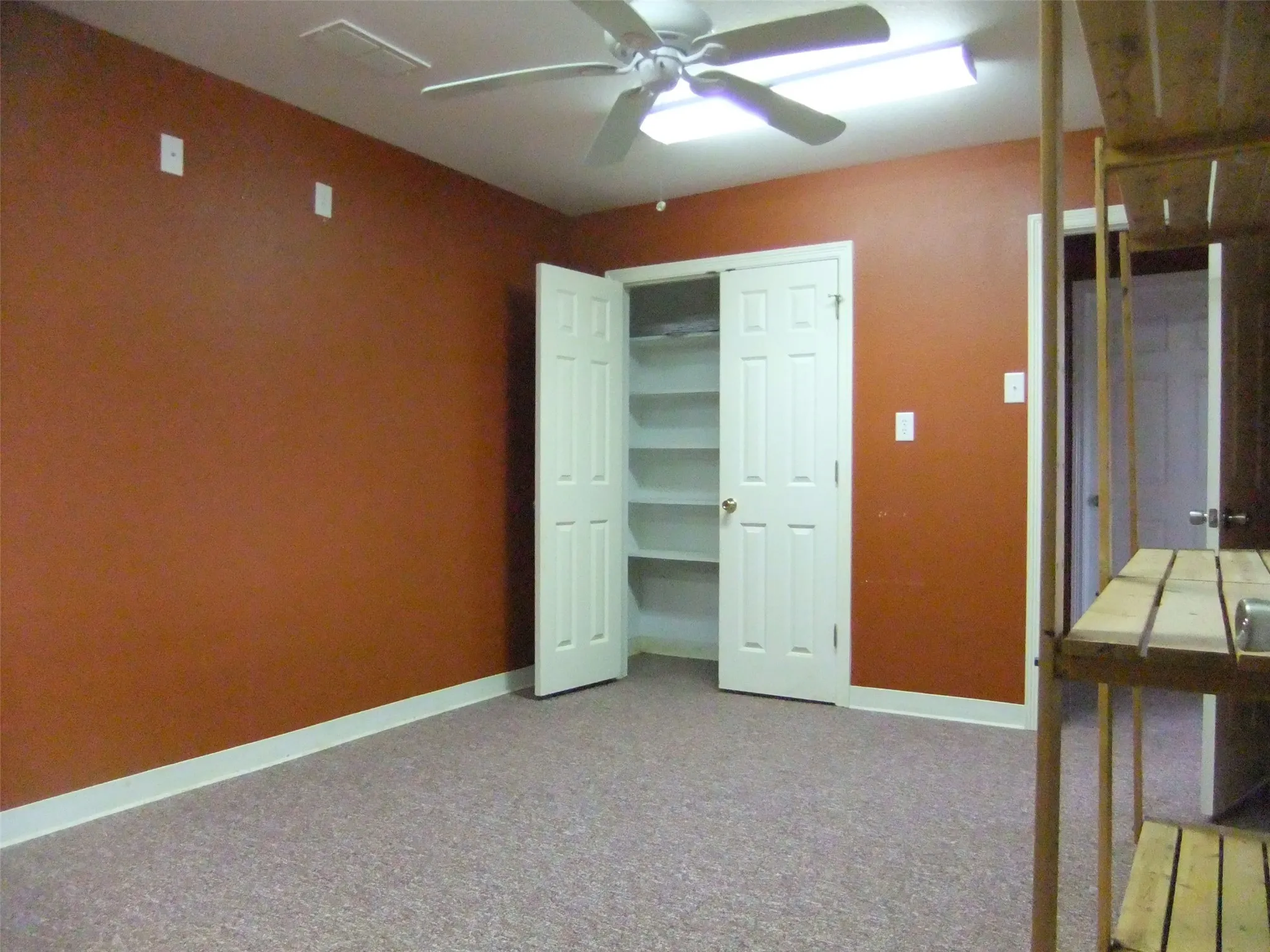 Dressing Room featuring a ceiling fan, fluorescent lighting, and a closet with bifold doors and built-in shelving