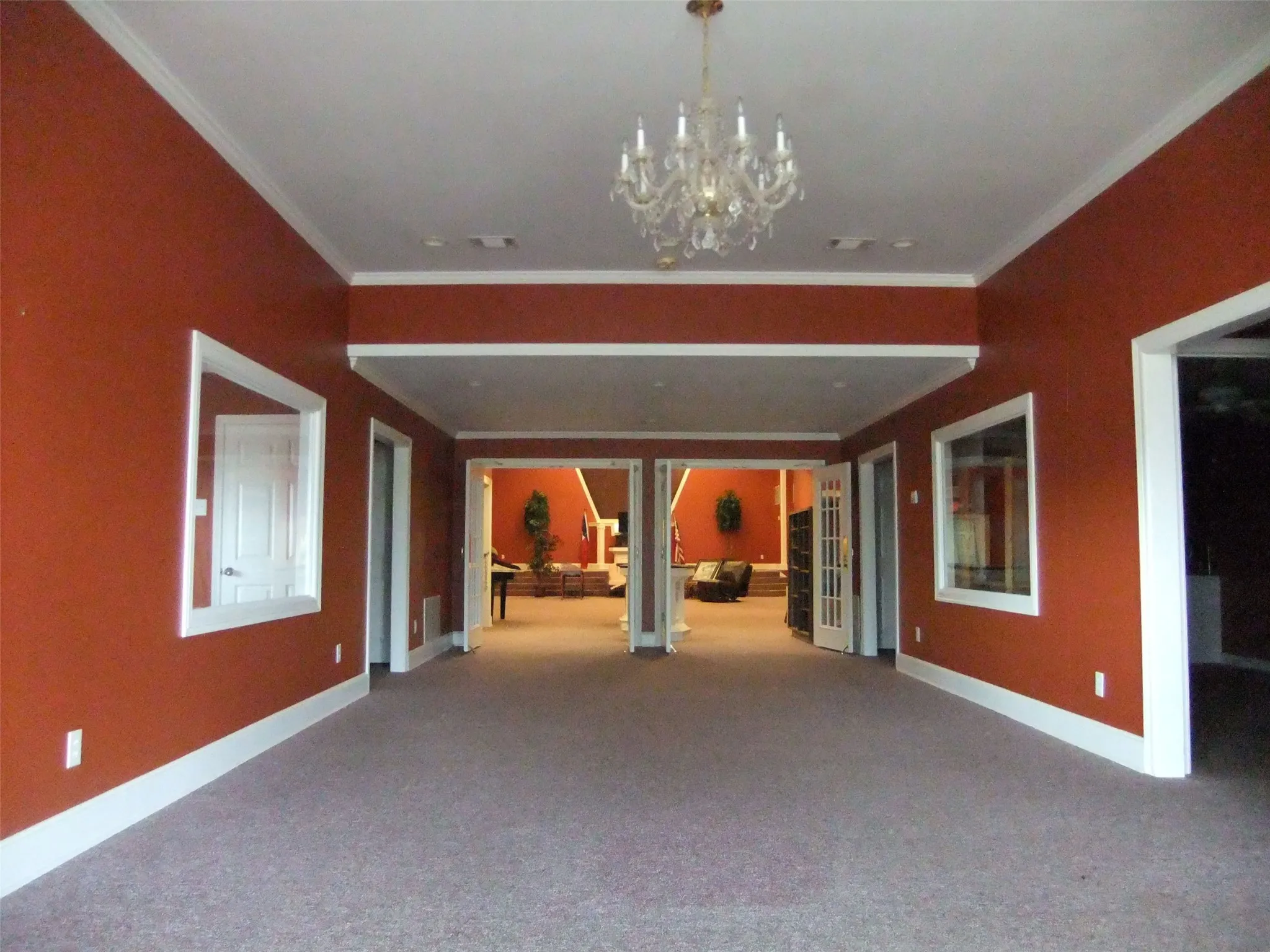 Spacious interior featuring a chandelier, crown molding, wide doorways, and neutral carpeting