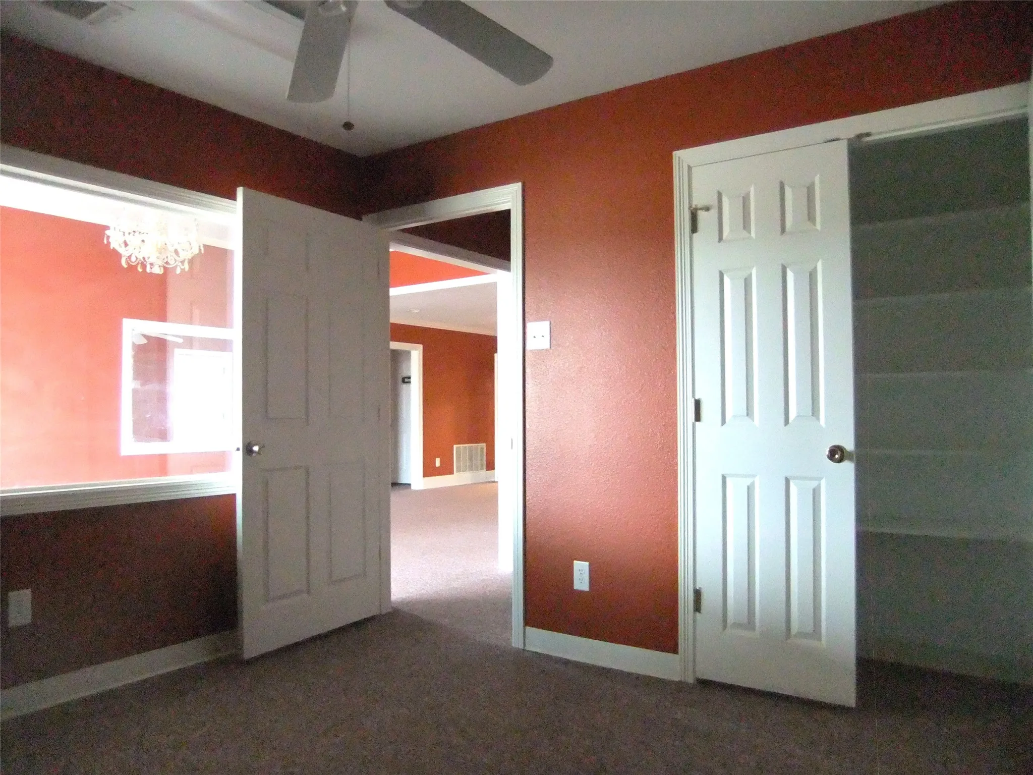 Carpeted flooring, ceiling fan, white paneled doors, and built-in closet shelving