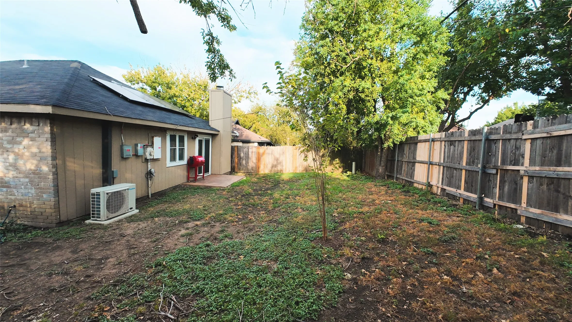 Spacious backyard with privacy fencing, a concrete patio, and mature trees