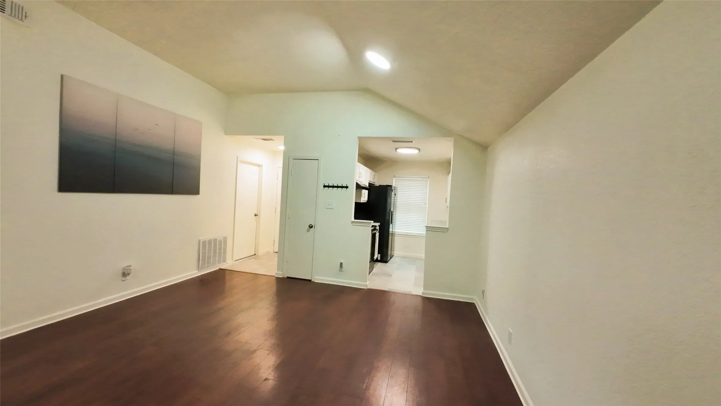 Vaulted ceiling, recessed lighting, wood-finish flooring, white walls, and bright trim