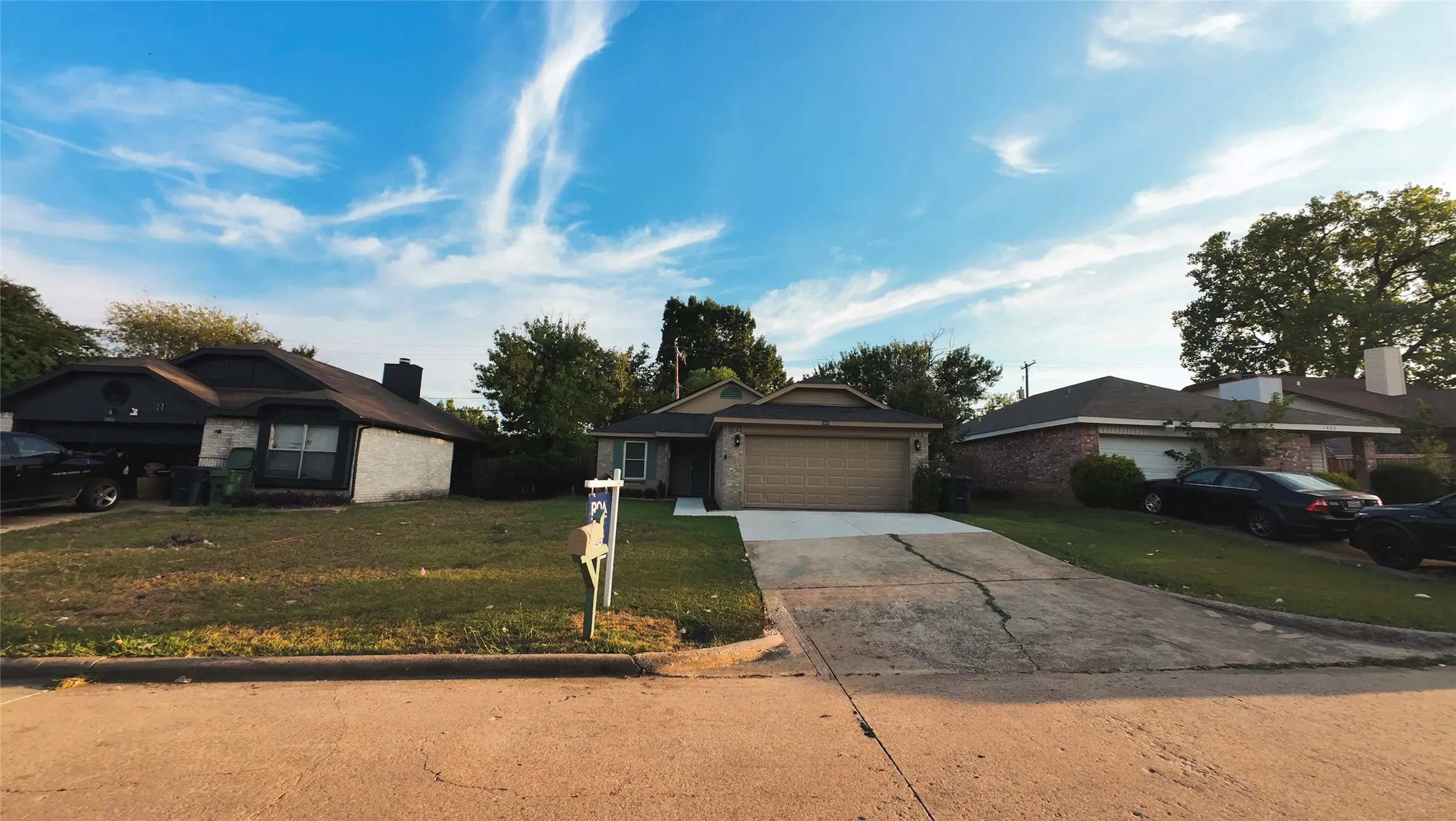 Front exterior with an attached garage, a paved driveway, and a front lawn