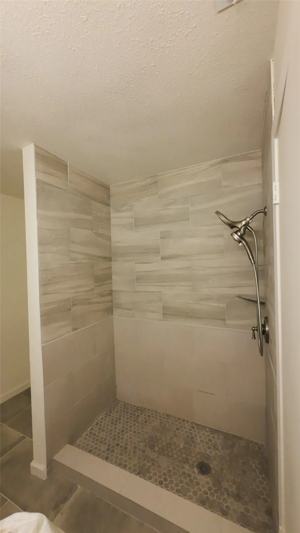 Walk-in shower with full tile surround, mosaic floor tiling, and a brushed nickel shower fixture