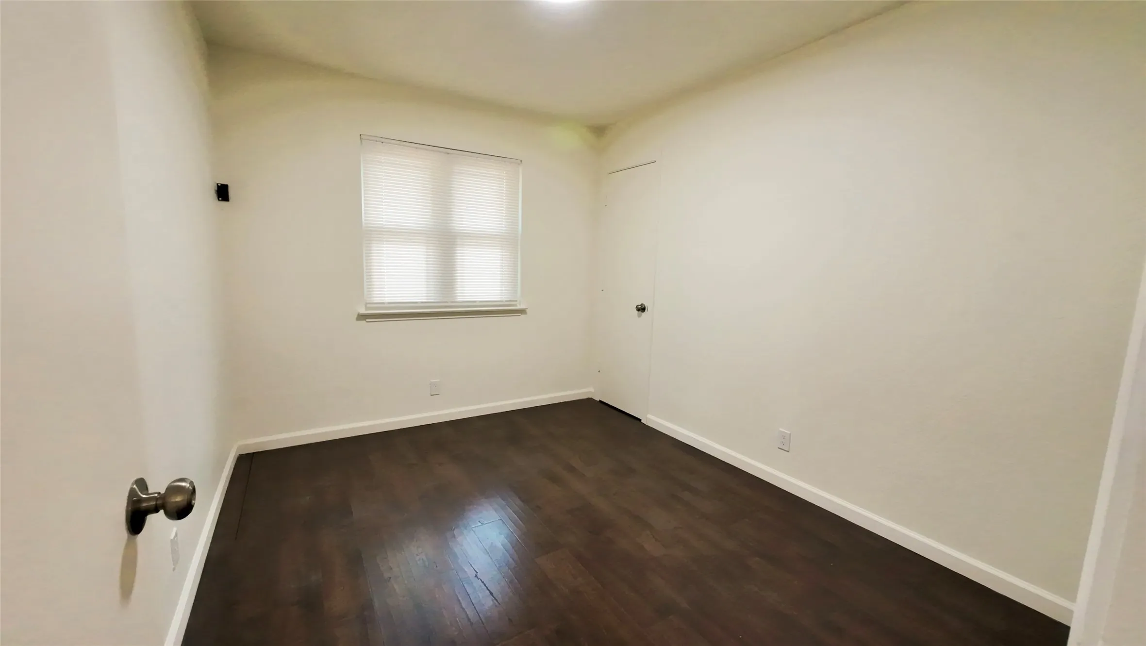 Wood-finish flooring, white walls, window with blinds, and ceiling-mounted lighting