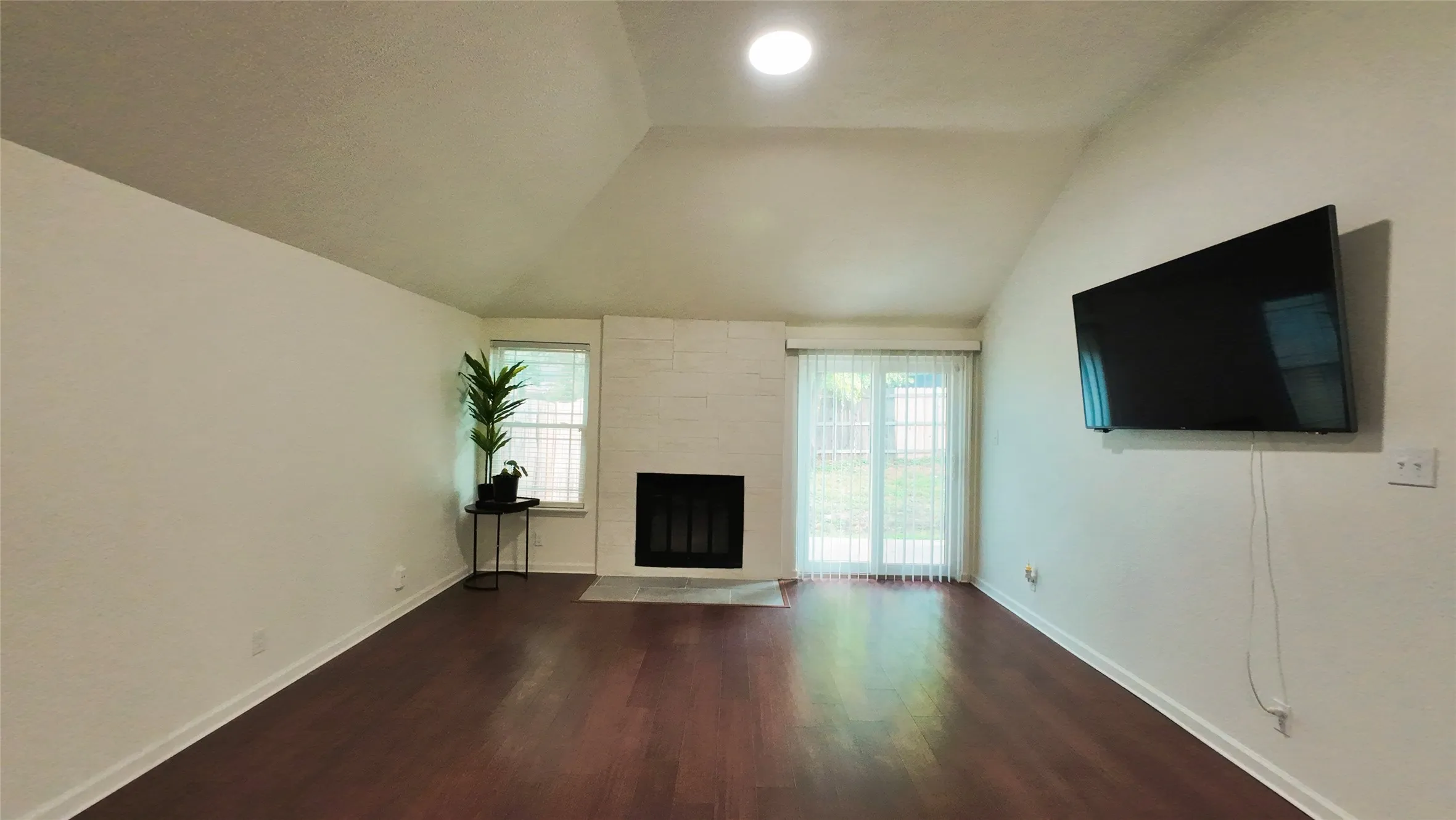 Vaulted ceiling, recessed lighting, wood-finish flooring, brick-surround fireplace, sliding glass door